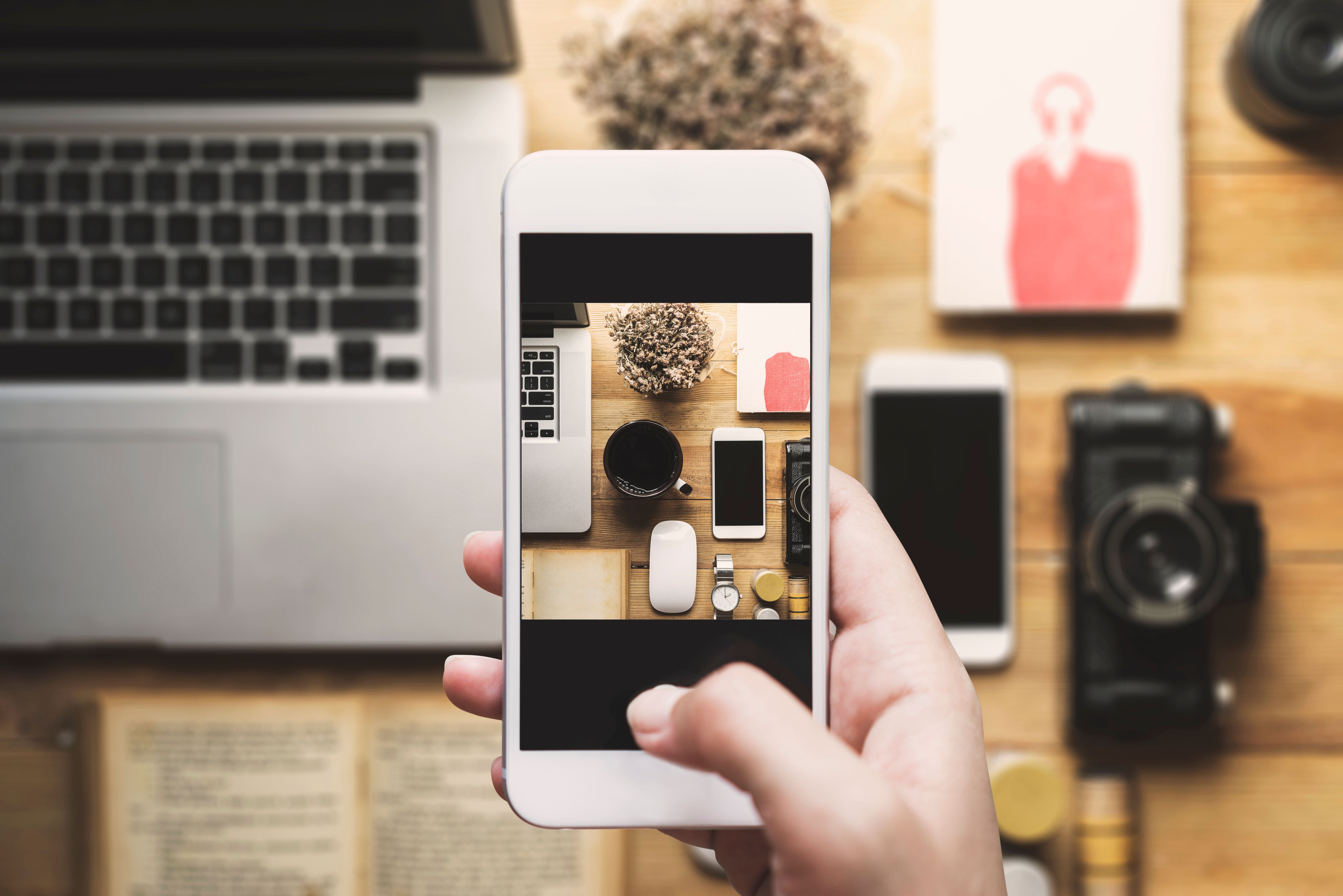 Hand taking photo with mobile phone, table top flat lay