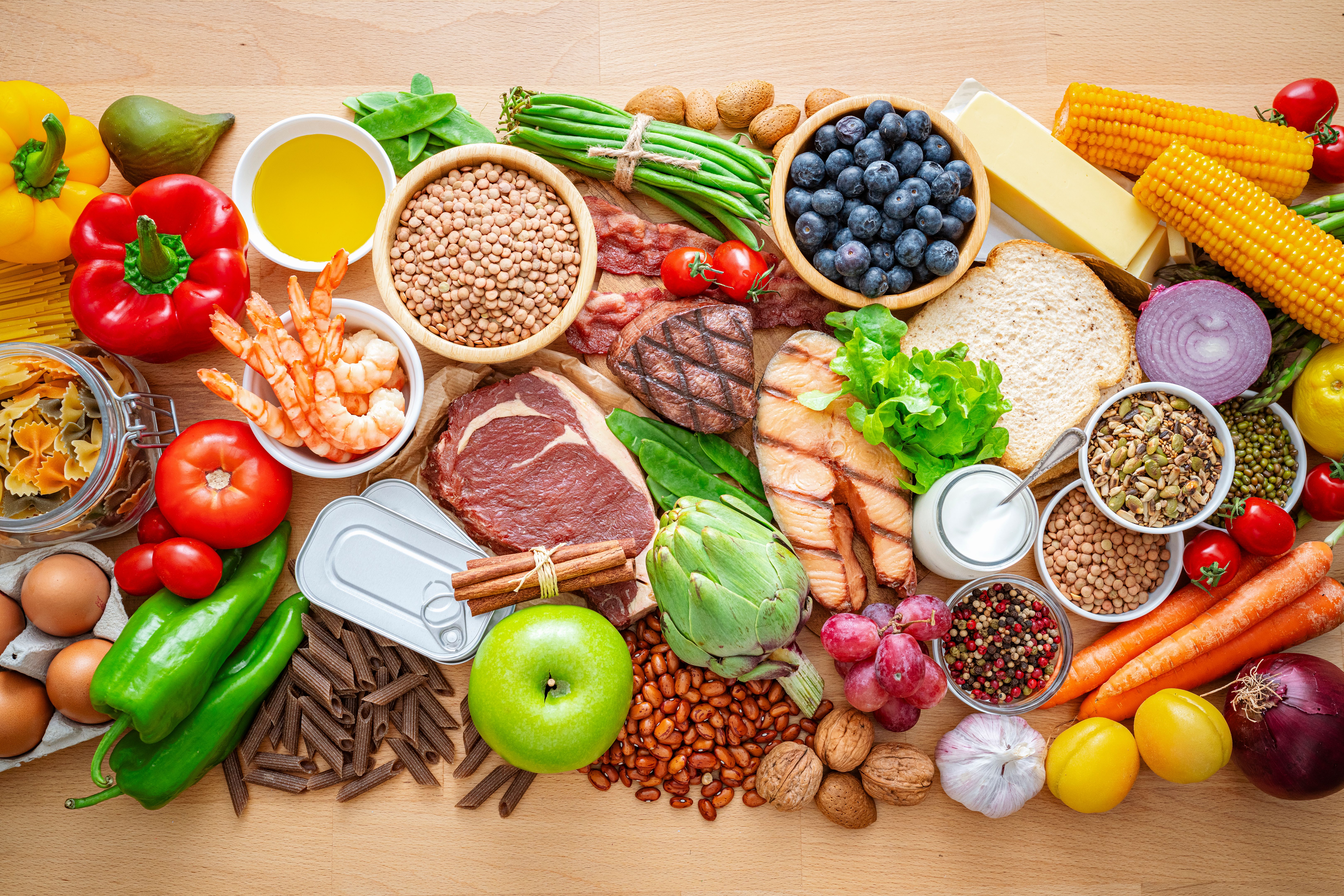 Table filled with large variety of food including fruits, vegetables meat, seafood, seeds and nuts, canned food, dairy products, legumes and spices Table filled with large variety of food including fruits, vegetables meat, seafood, seeds and nuts, canned food, dairy products, legumes and spices