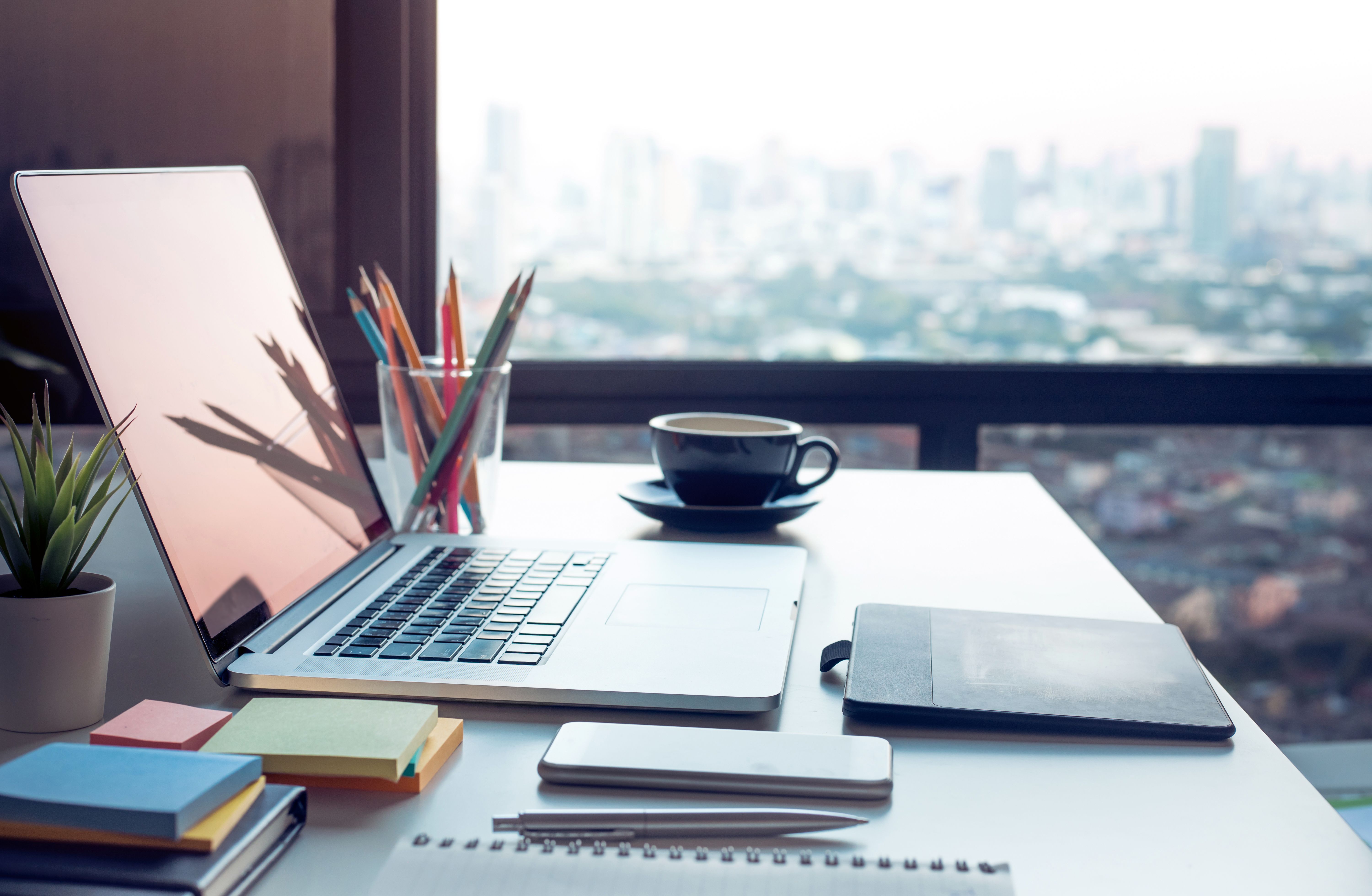 Moderne Arbeitstisch mit Computer Laptop und Stadtansichten Aussicht vom Fenster. Business-Konzepte-Ideen