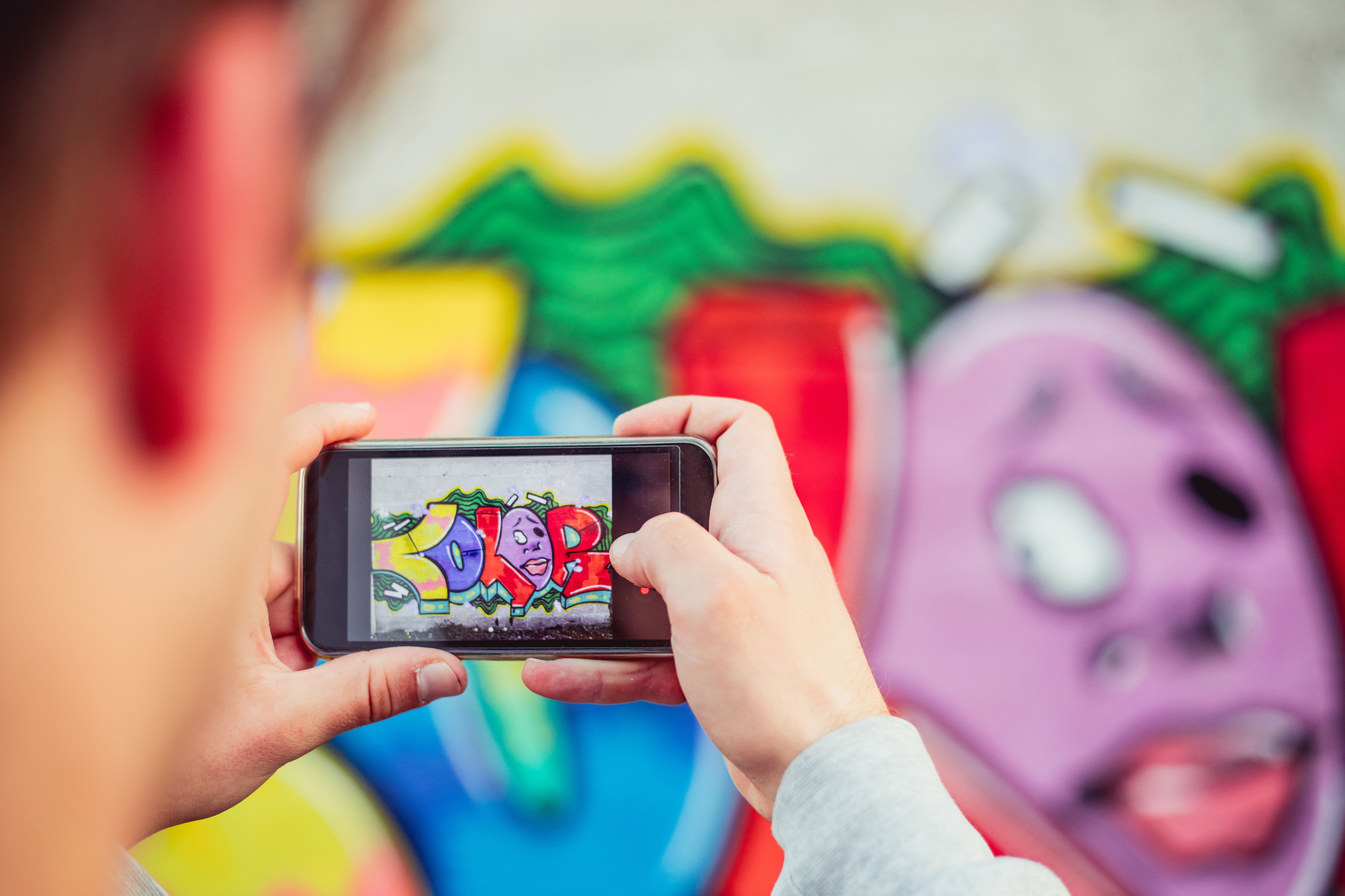 Young Man Taking a Photo of Graffiti with his Smart Phone