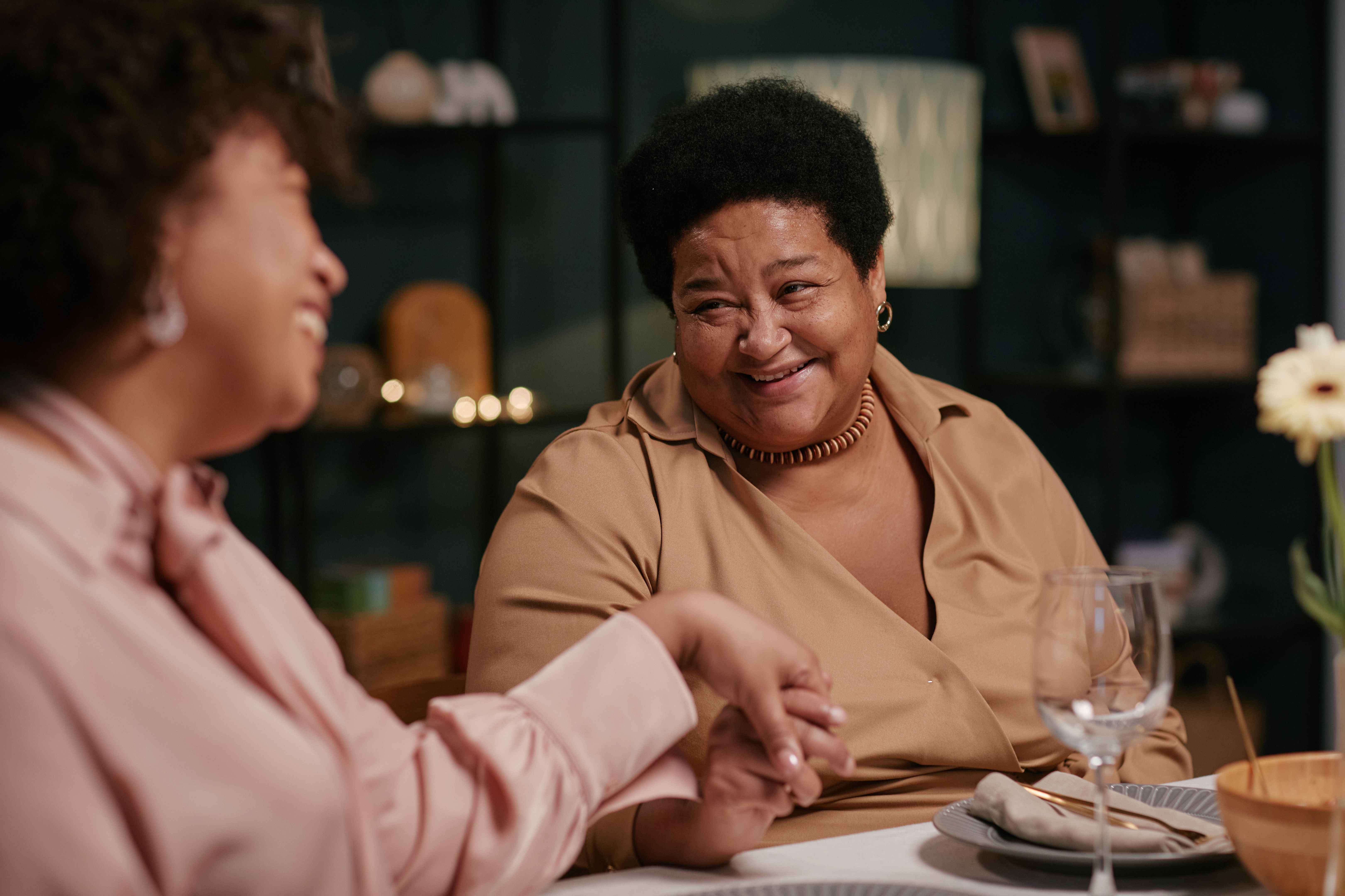Happy Senior African American Woman Conversing with Family during Dinner Happy Senior African American Woman Conversing with Family during Dinner
