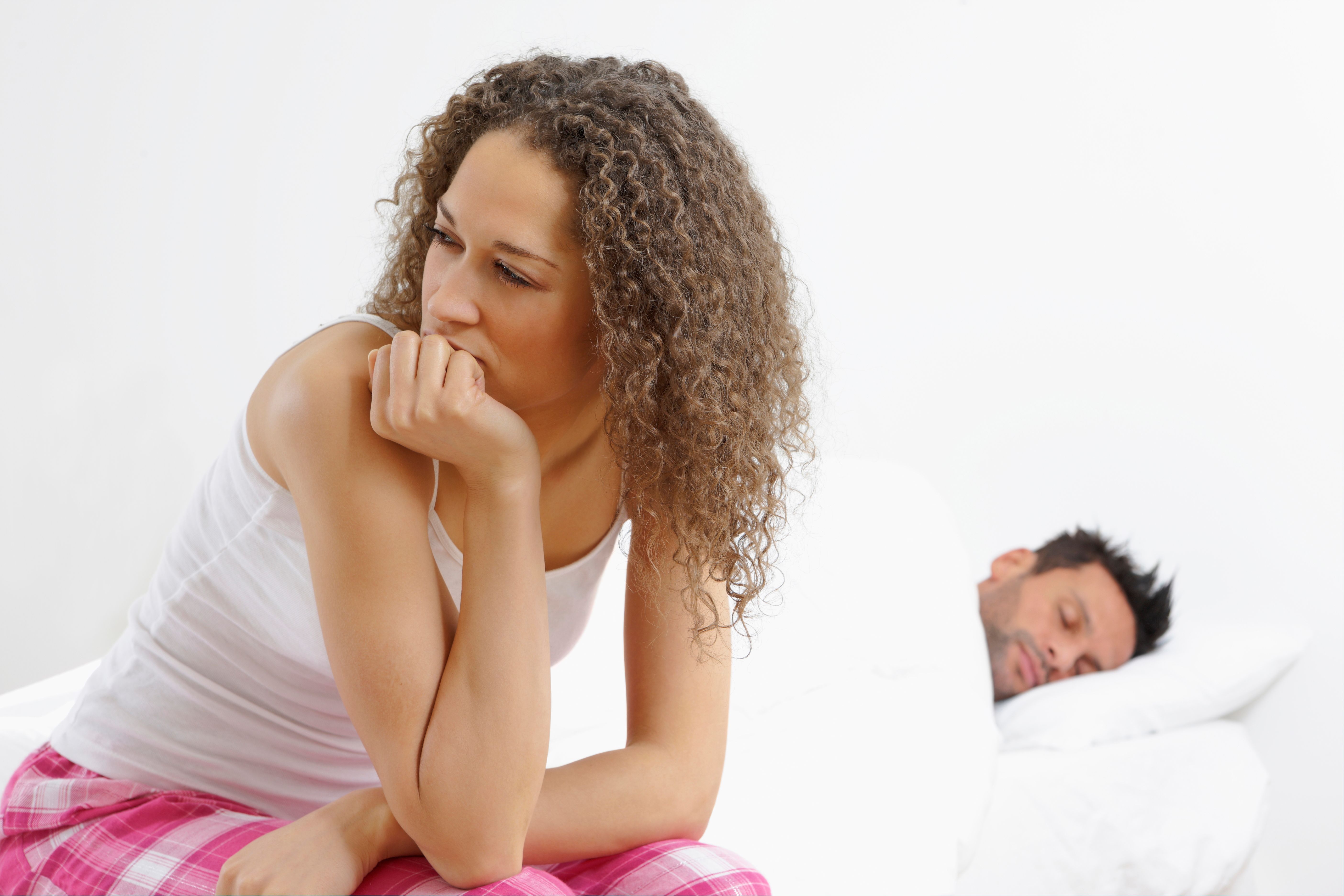 Malestar mujer sentada en la cama después de haber fila con amor