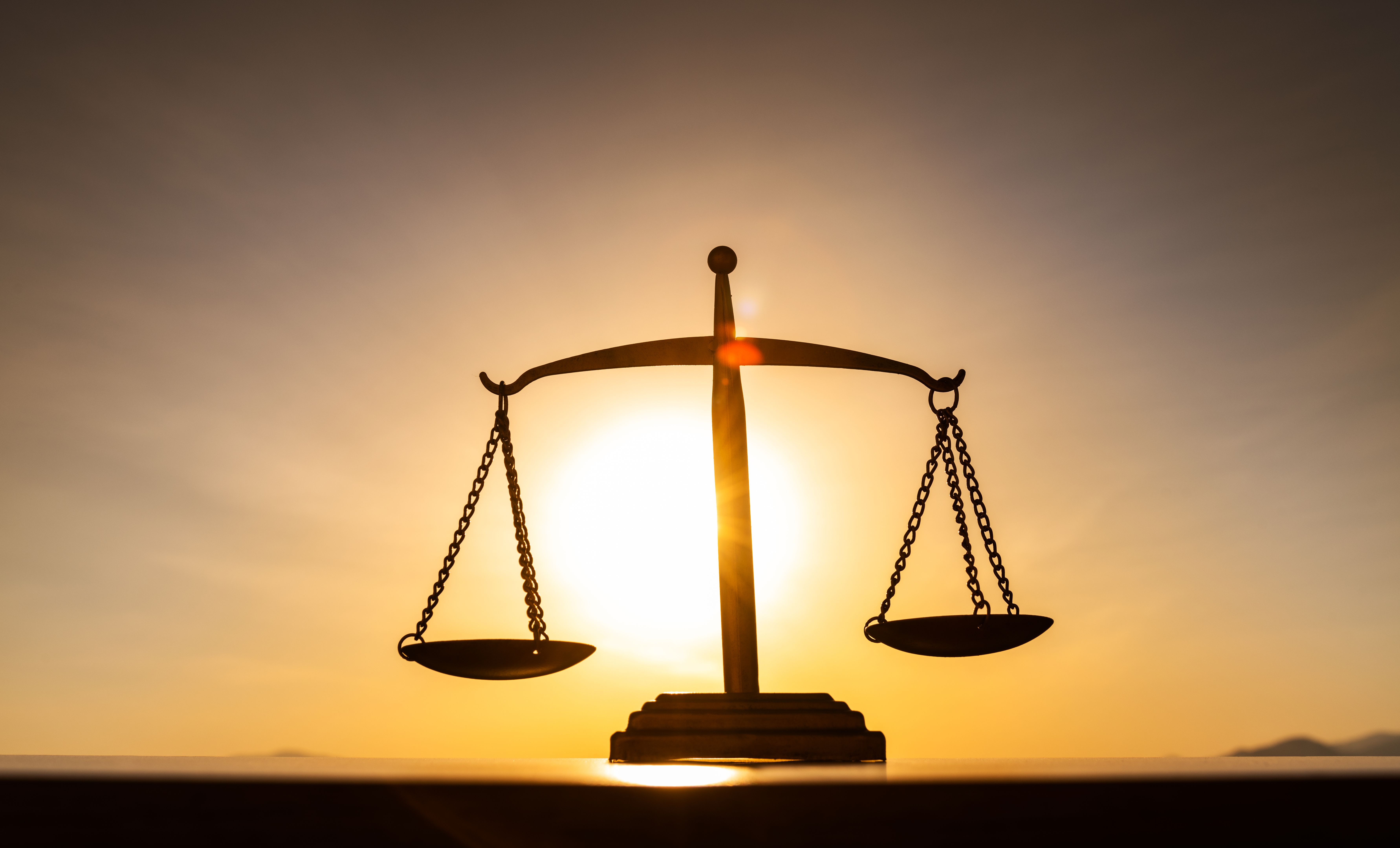 Silhouette of a balance scale against sunset sky
