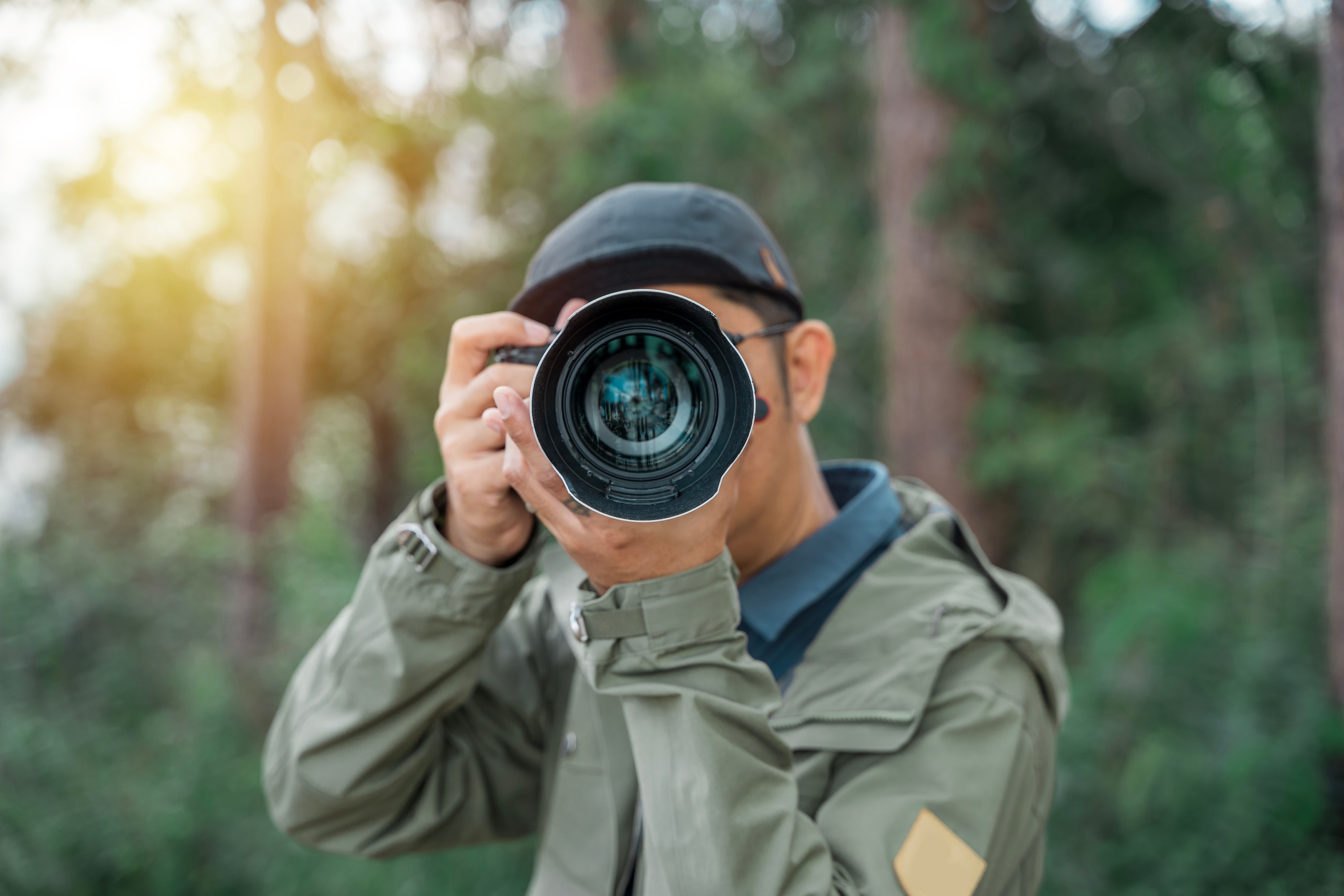 Young man photographer takes photographs with dslr camera in a city. Travel, vacations, professional freelance work