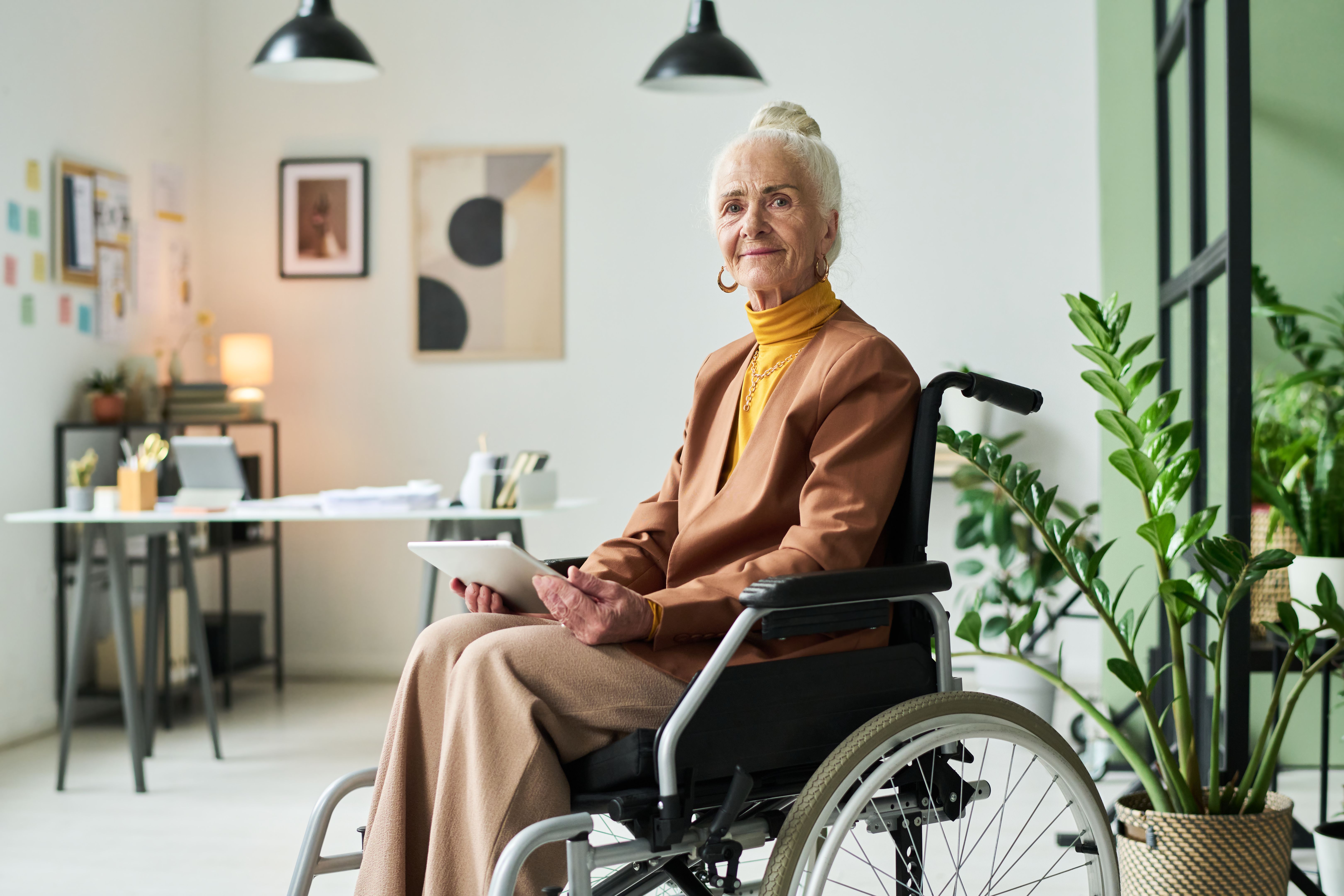 Senior Woman in Wheelchair Holding Tablet in Modern Office Azalea House in Altadena Senior Woman in Wheelchair Holding Tablet in Modern Office Azalea House in Altadena
