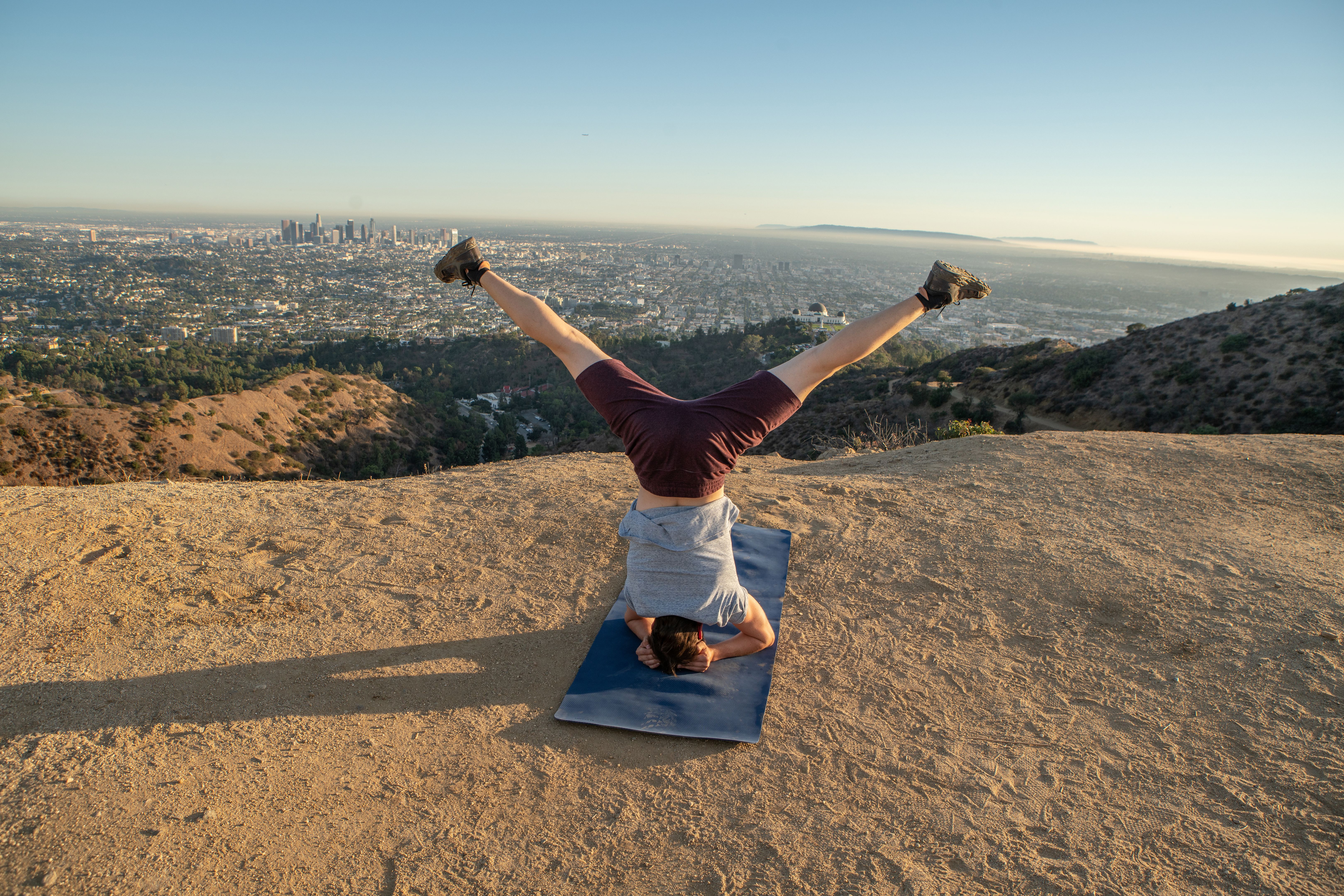 Young man exercising yoga upside down position holding headstand at sunset Young man exercising yoga upside down position holding headstand at sunset