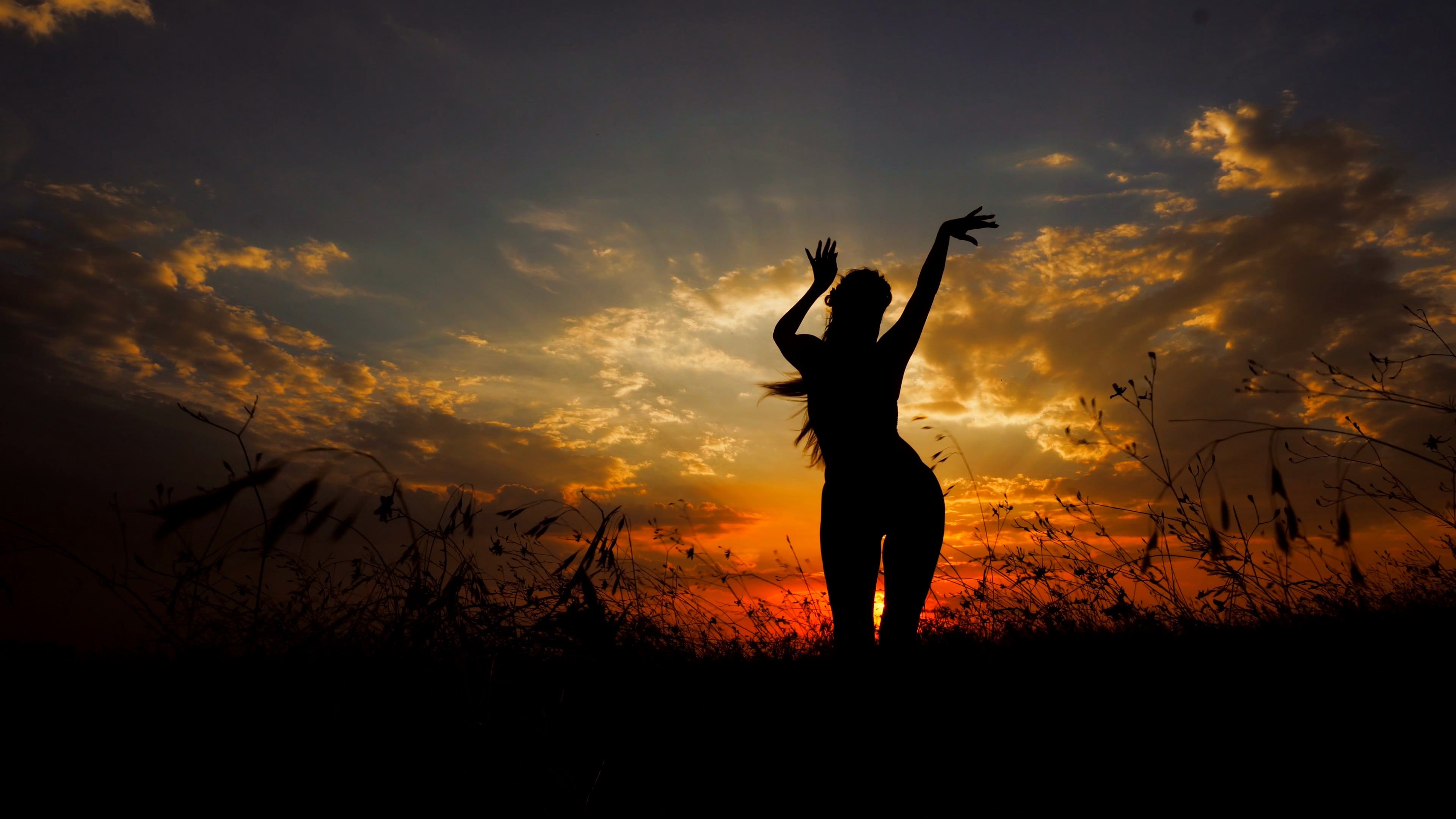 Female person doing yoga in steppe, silhouette in sunset background
