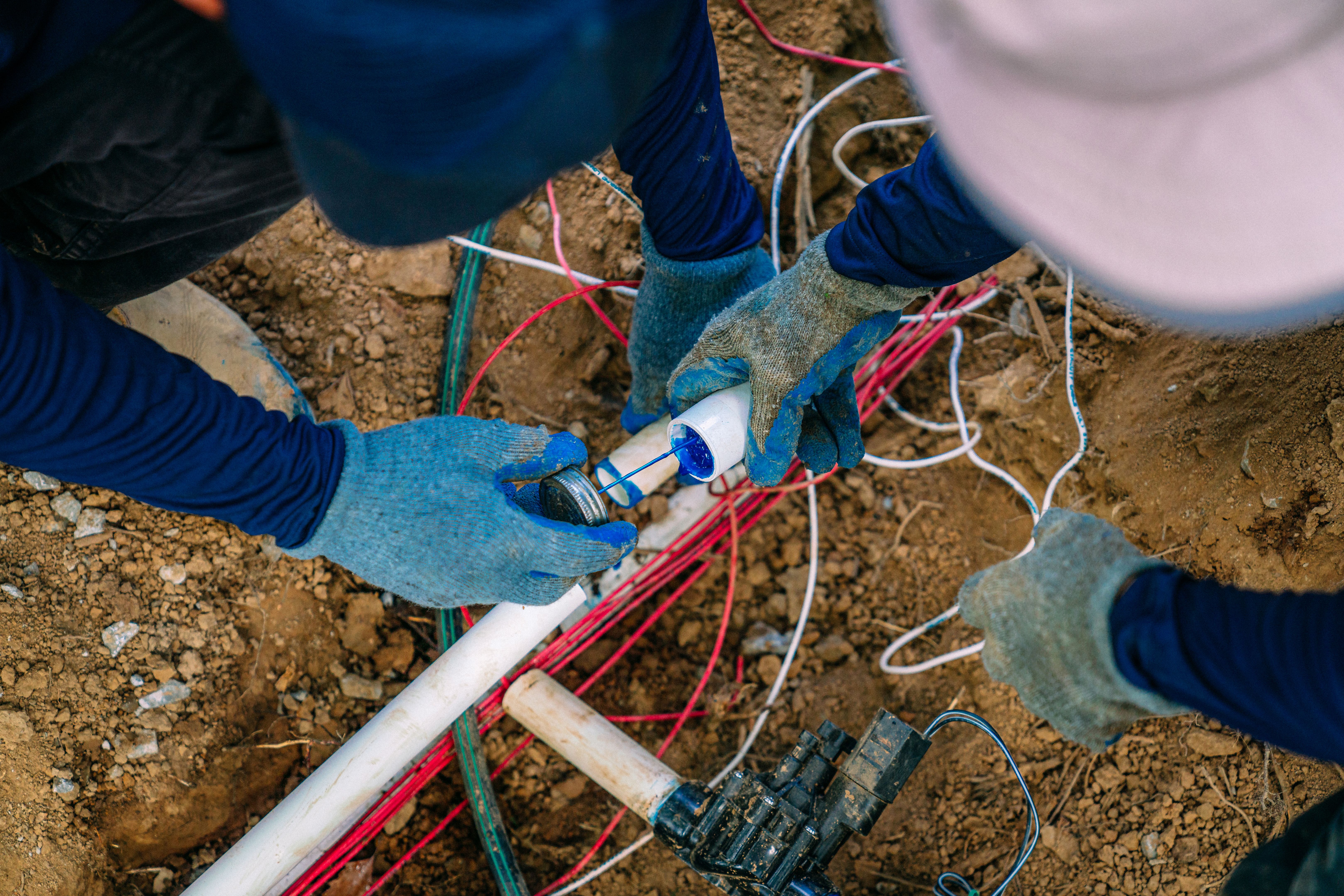 Irrigation Construction Workers using Blue PVC Cement on underground Sprinkler Pipe