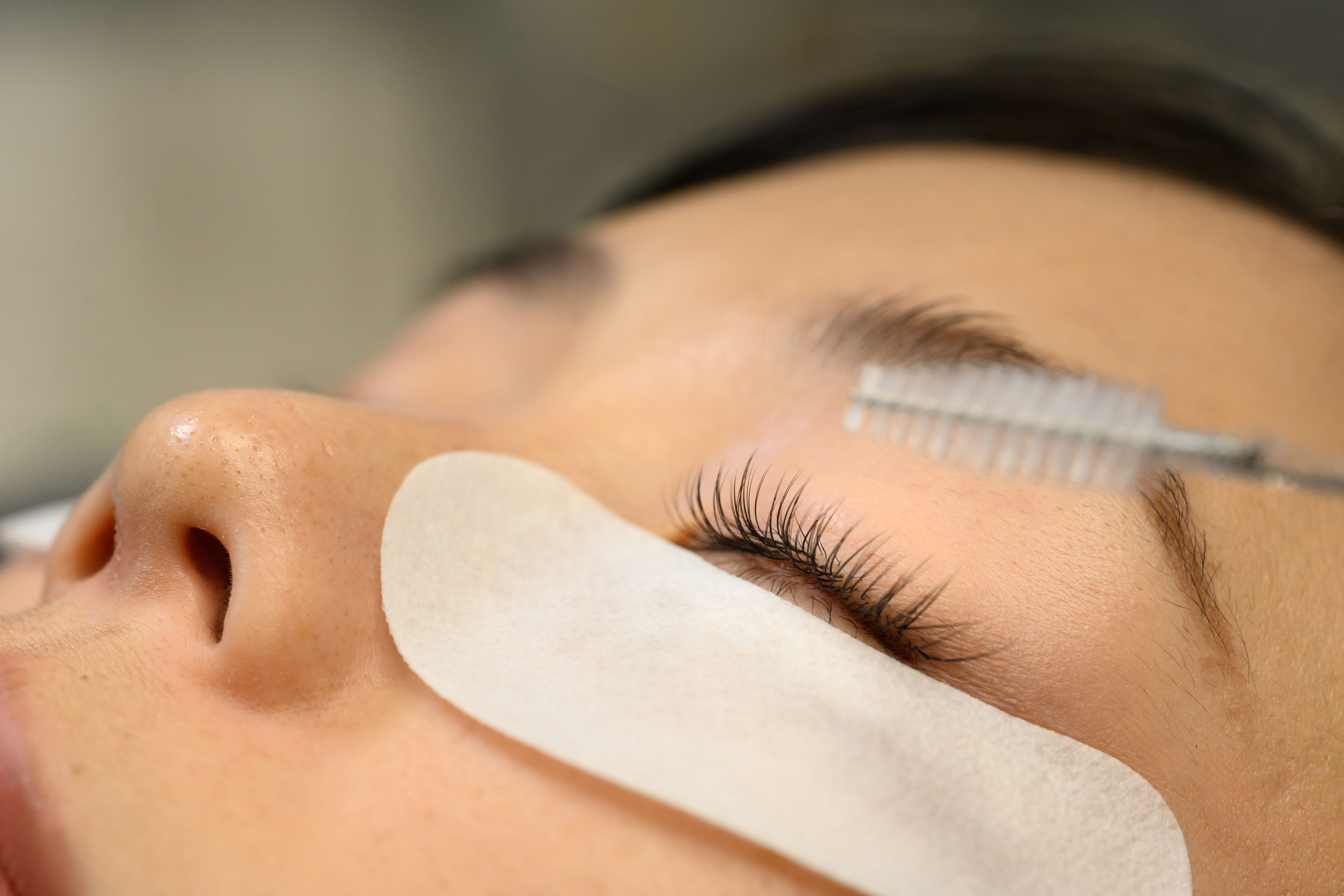 Close up of freshly applied eyelash extensions being brushed with a spoolie tool