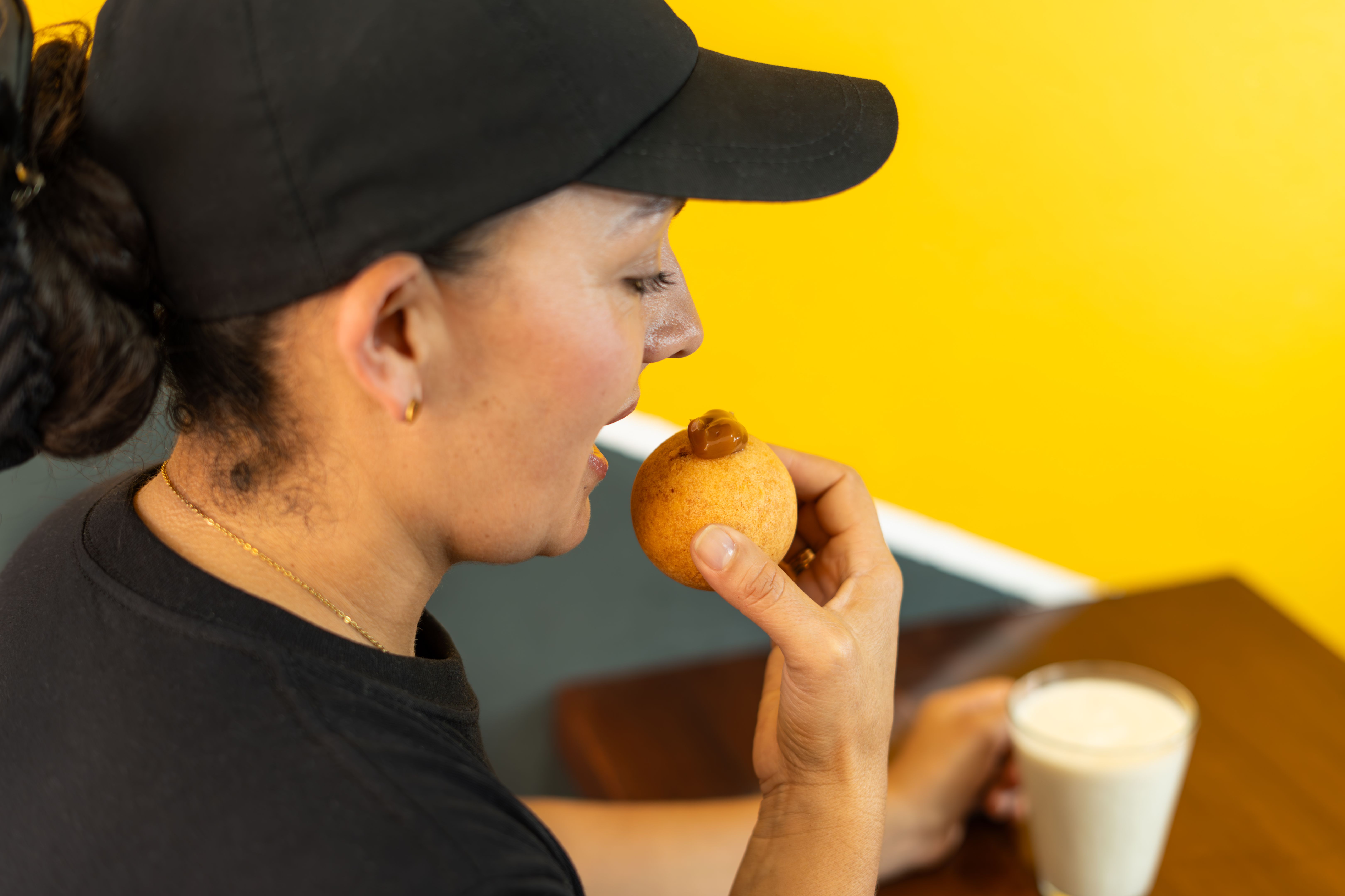 A woman enjoys a delicious bunuelo or cheese bun filled with caramel sauce , accompanied by creamy oatmeal.