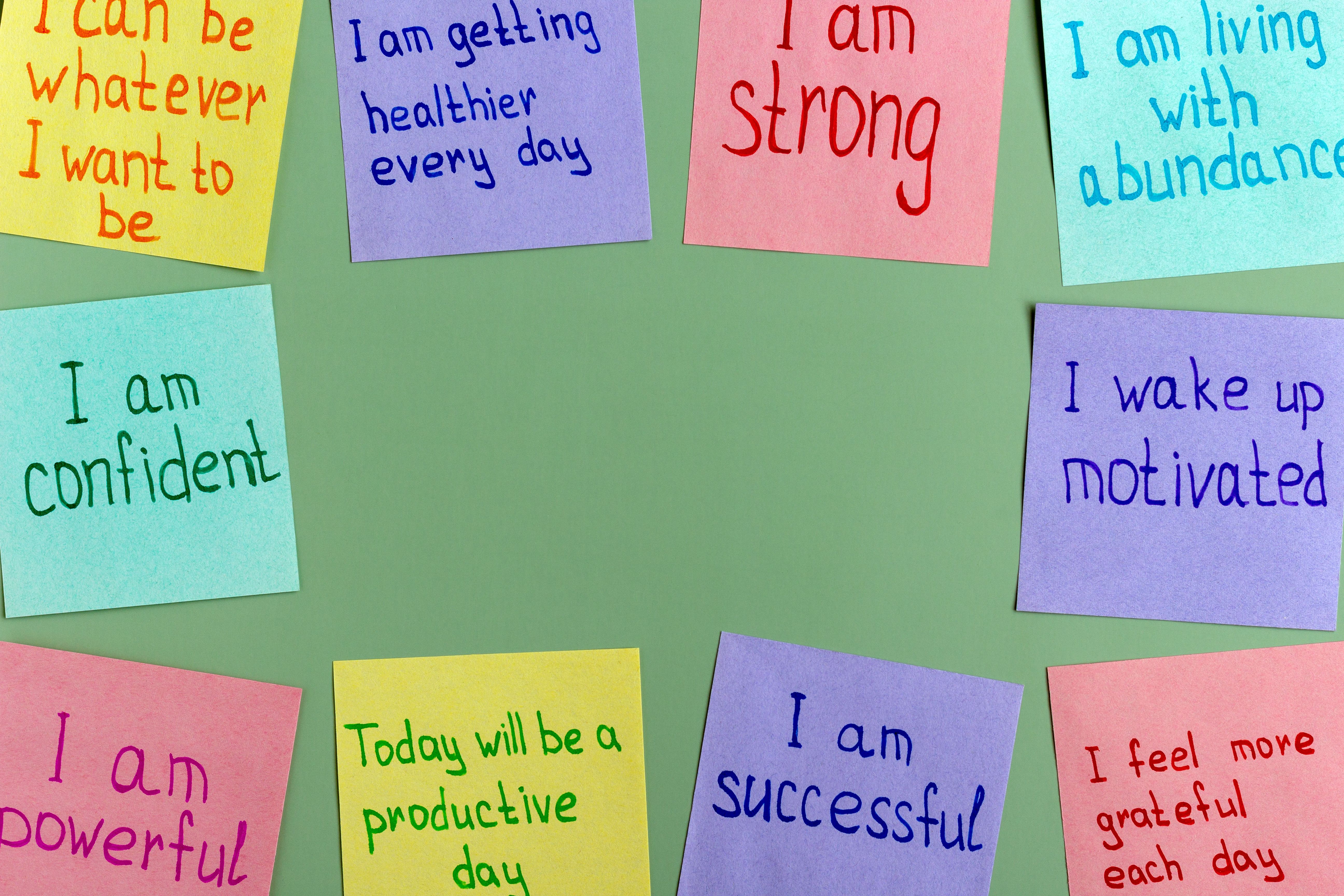 Positive affirmations for every day - words on multi-colored on paper for notes on a green background.