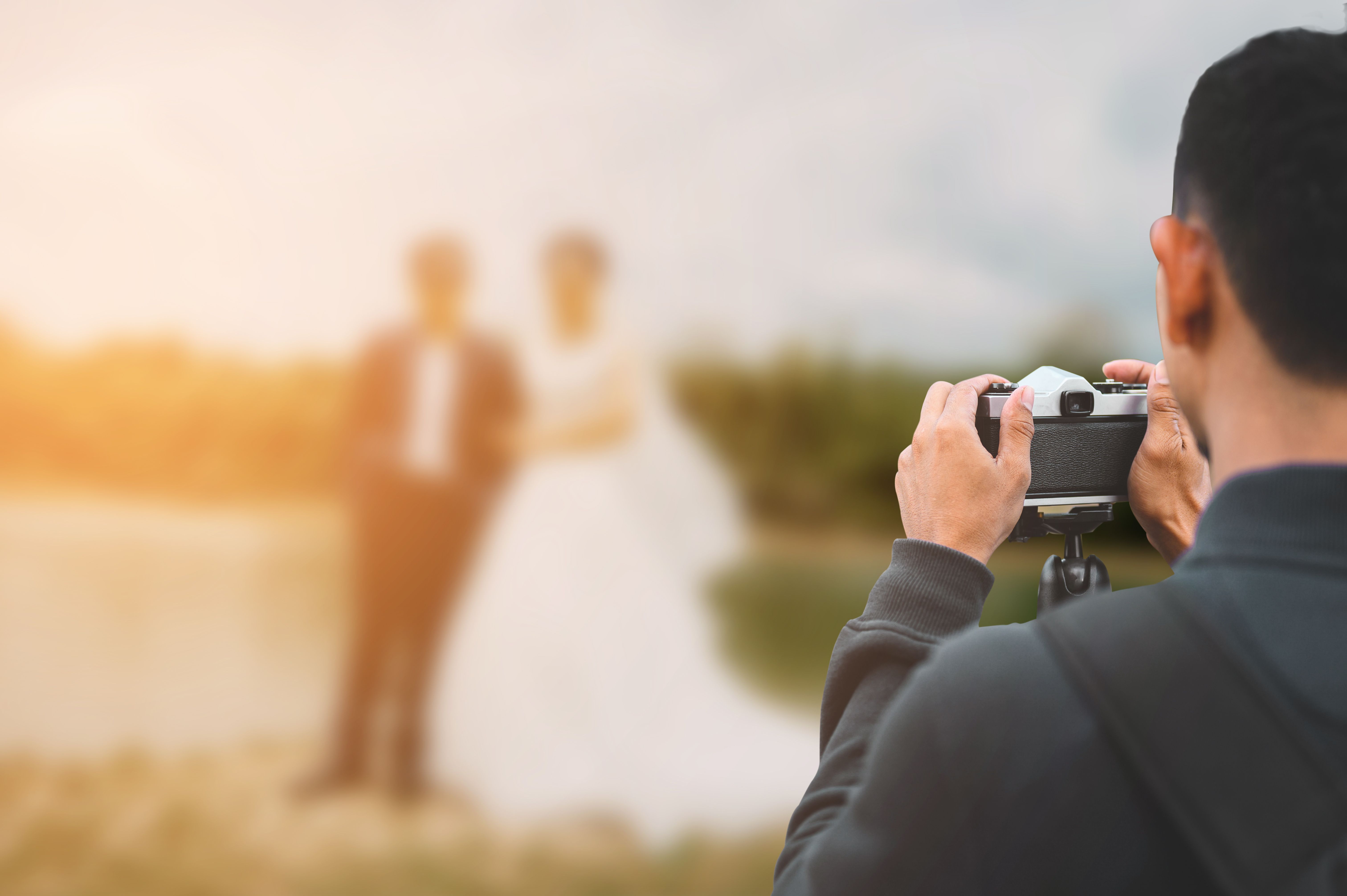 Male photographer taking wedding photos of newlyweds