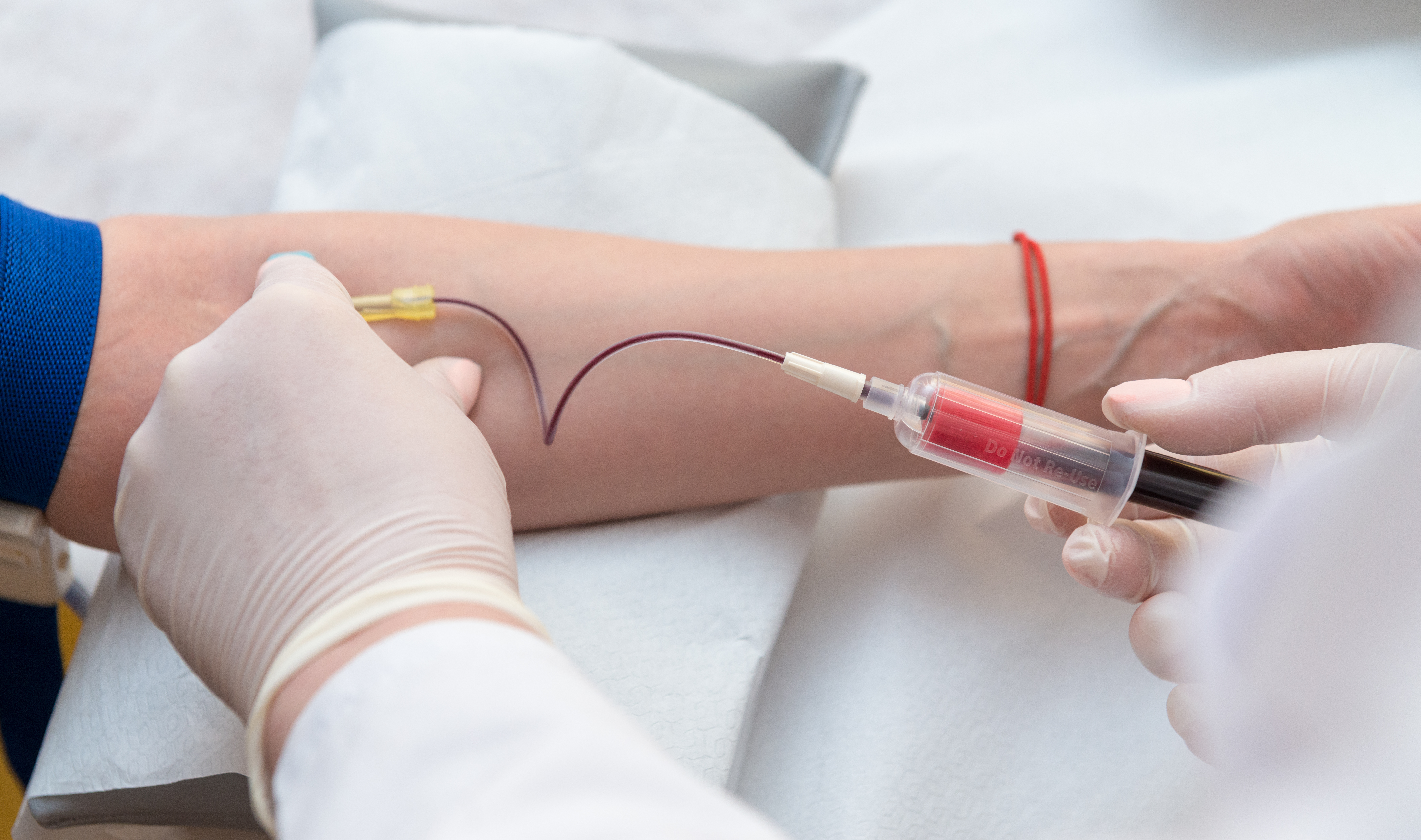 Doctor hands sticking needle into female vein for blood sampling
