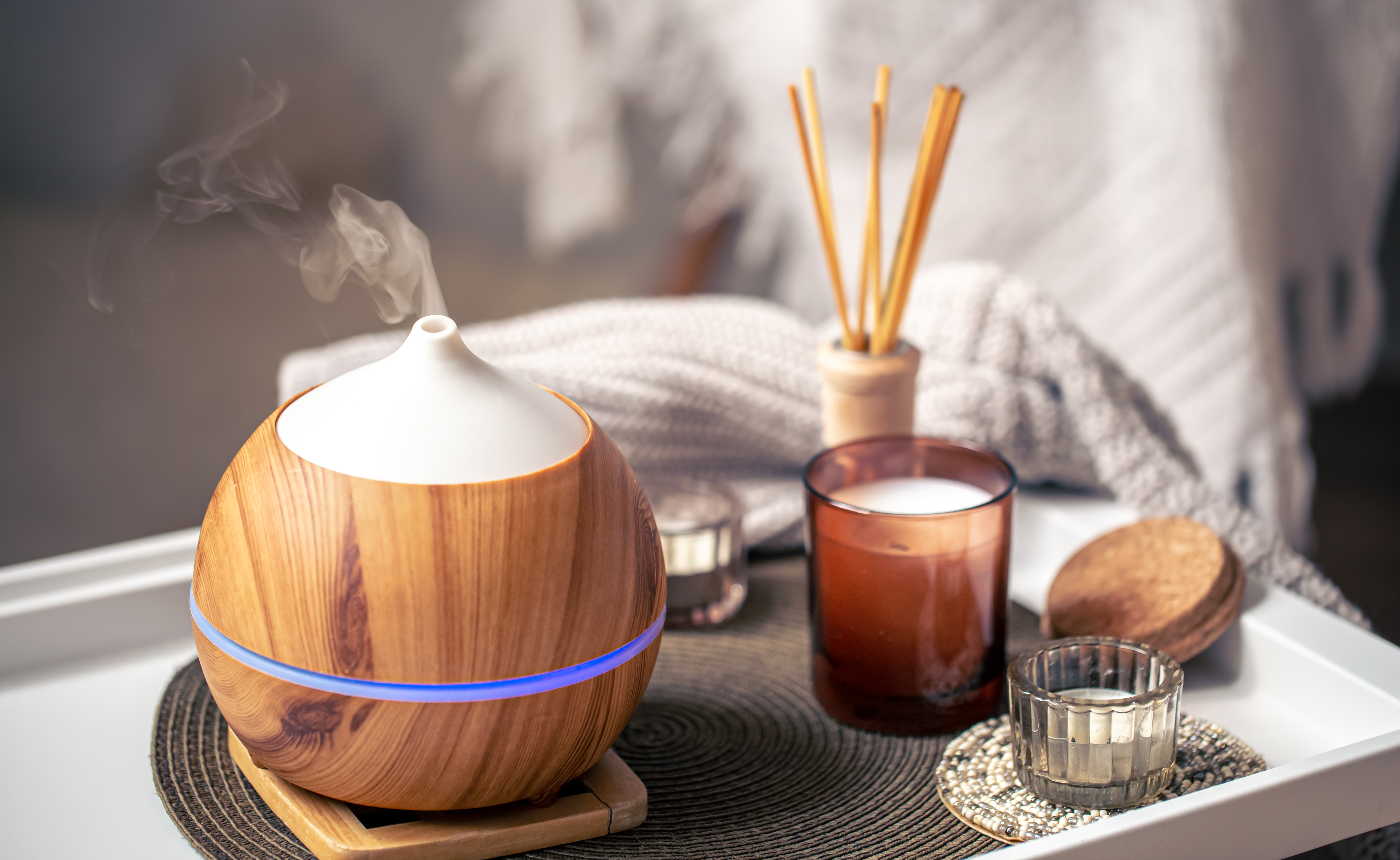 A cozy composition with an aroma diffuser and candles in a home interior.