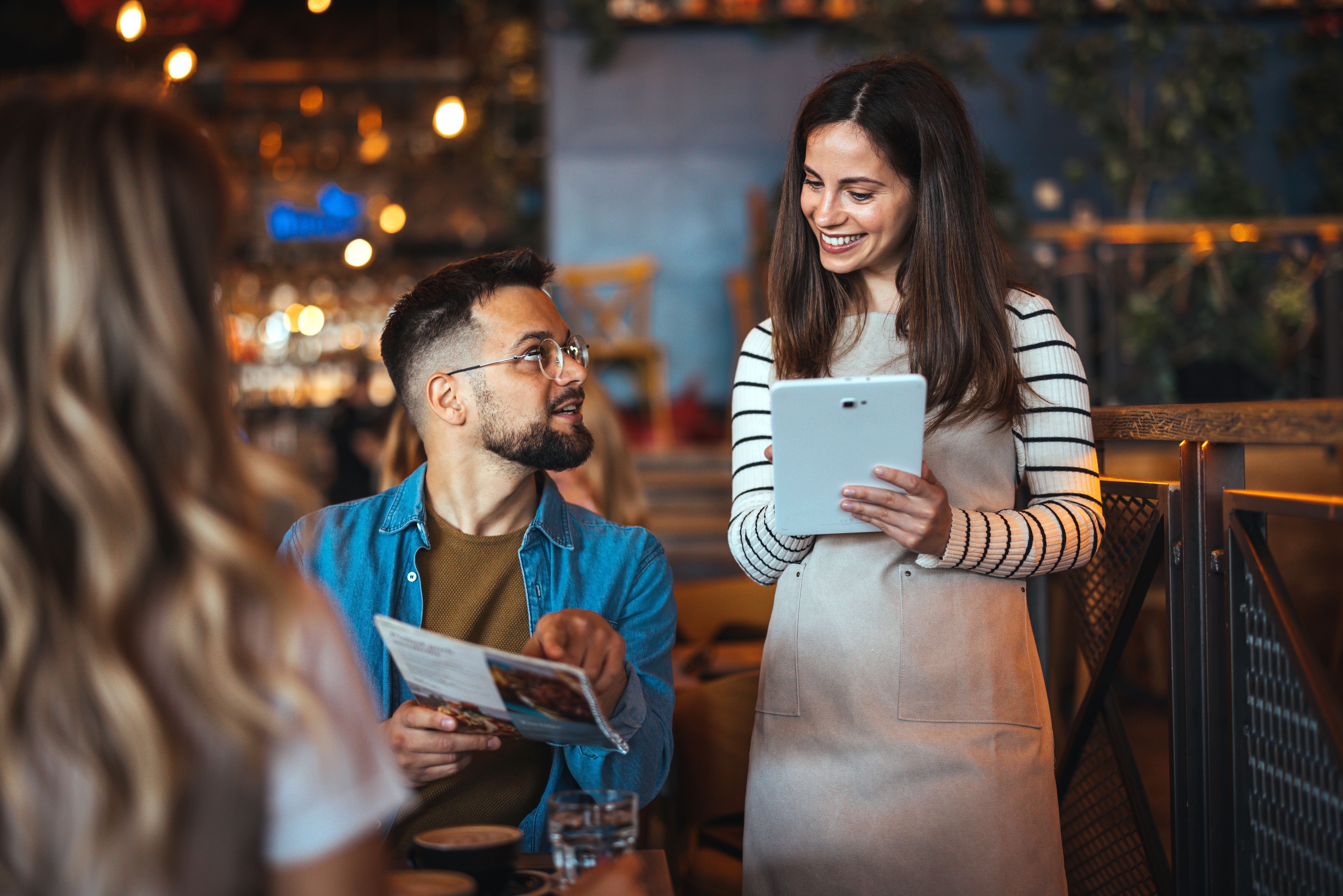 Friendly Bar Interaction Between Diverse Patrons and Waitress
