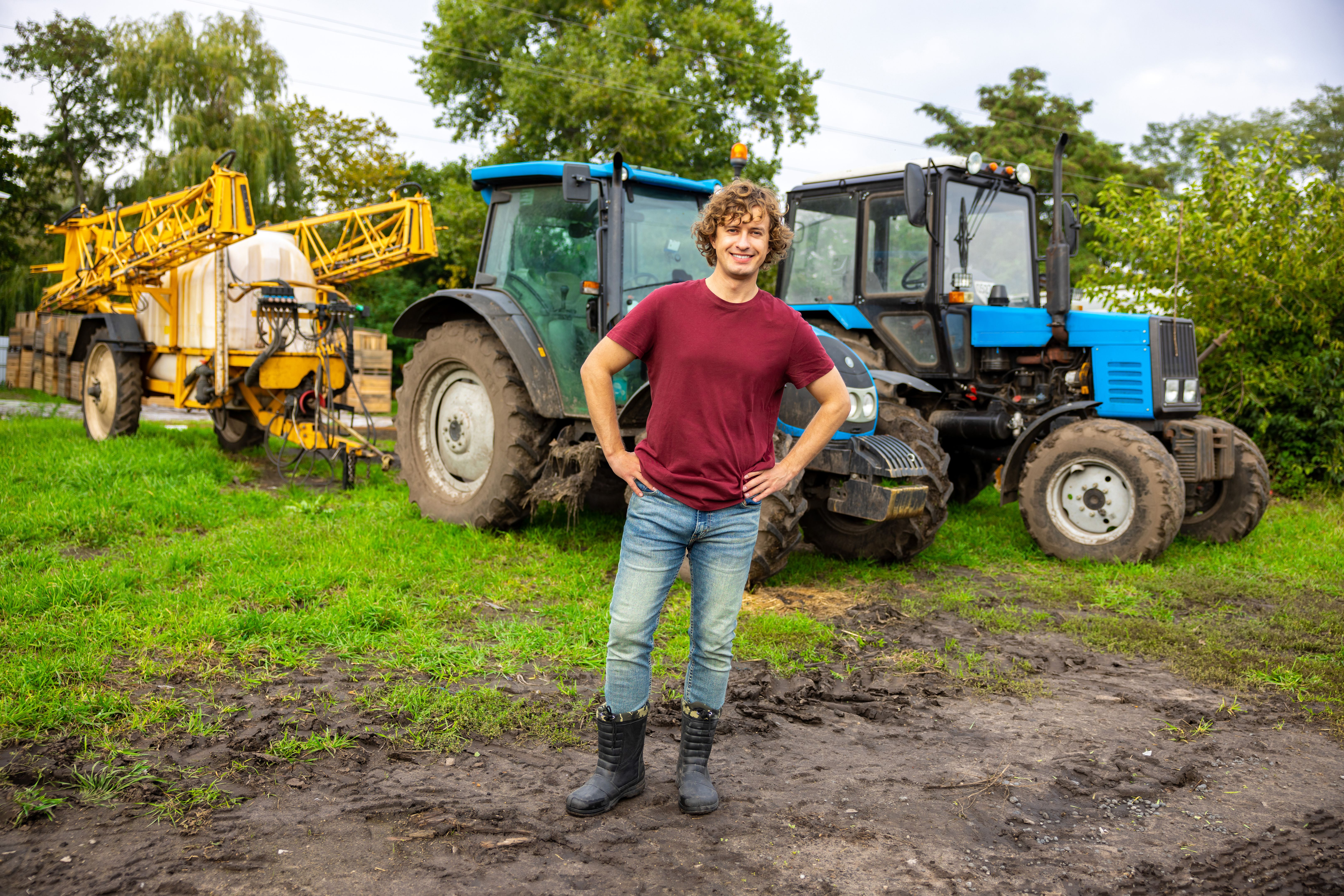 Joyous farmer standing in front of the tractor