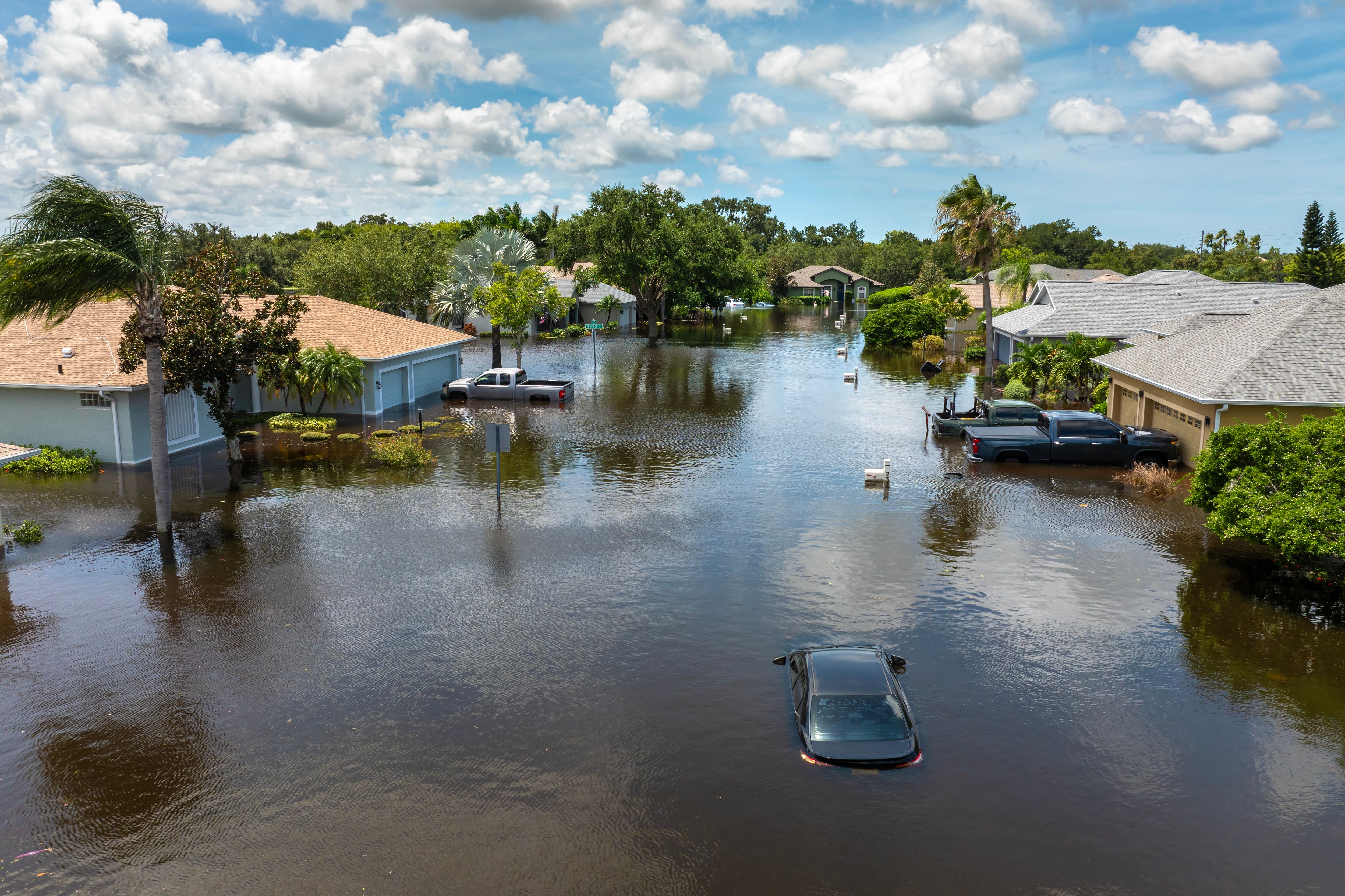 Hurricane rainfall flooded road. Drowned car on city street in Florida residential area. Consequences of hurricane natural disaster