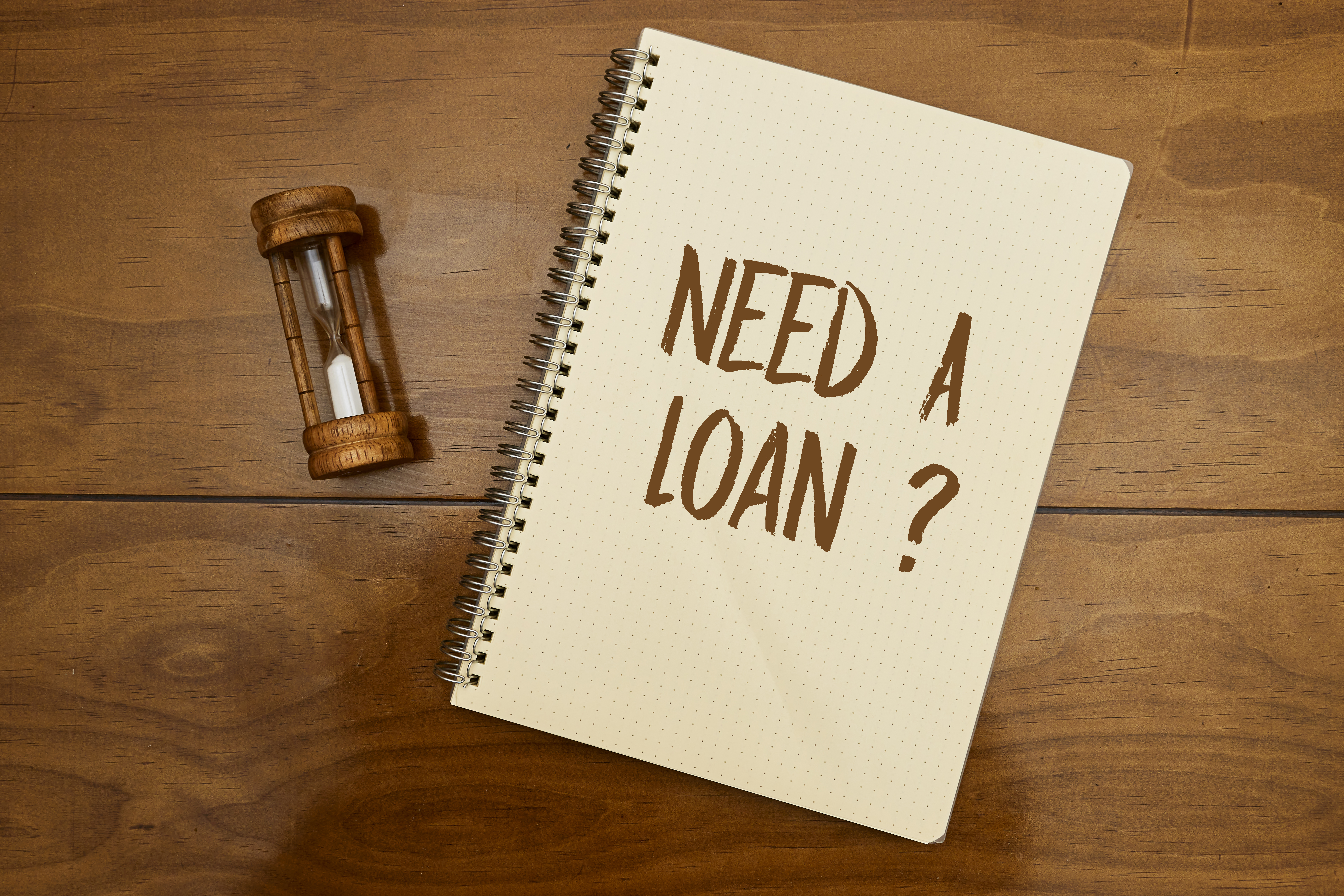 Sand running through the bulbs of an hourglass measuring the passing time in a countdown to a deadline with need a loan concept