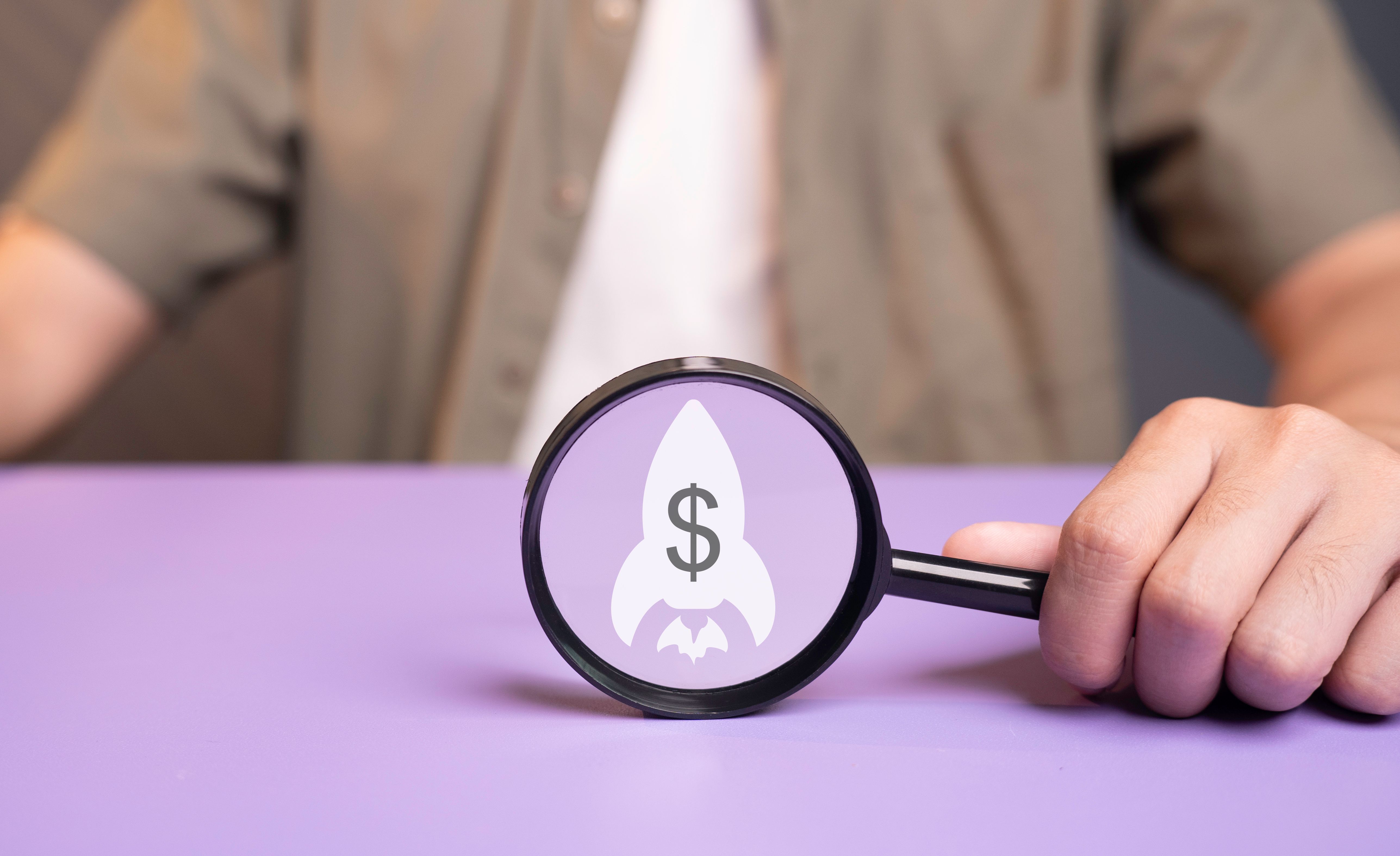 Magnifying glass showing revenue growth, financial target profit, rocket icon and dollar currency symbol, business income generating concept. Planning, future development of the organization.