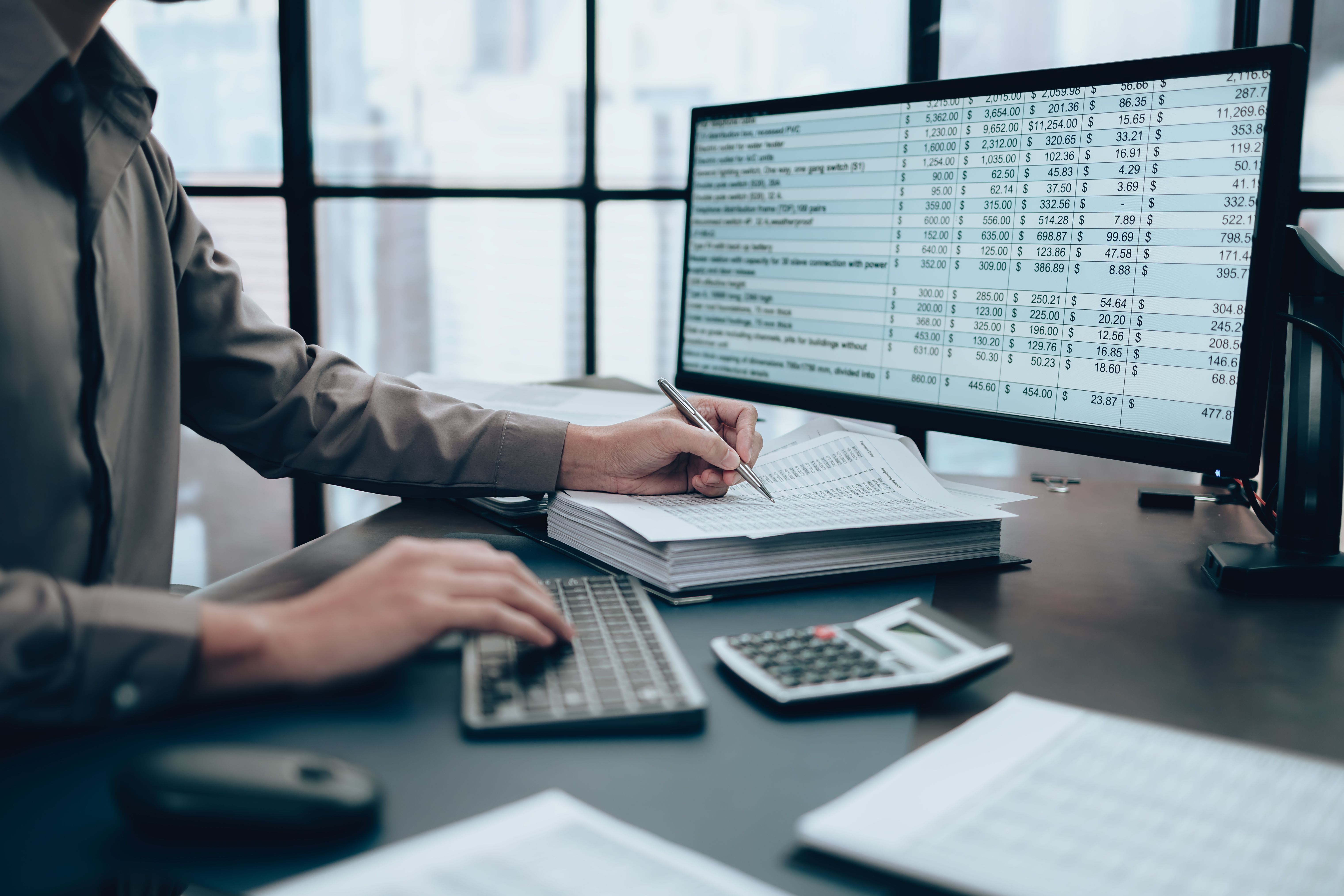 Investors working on desk office and using a pan and pointing to check tracking cost, balance, profit and  currency. Accounting and  Financial concept.
