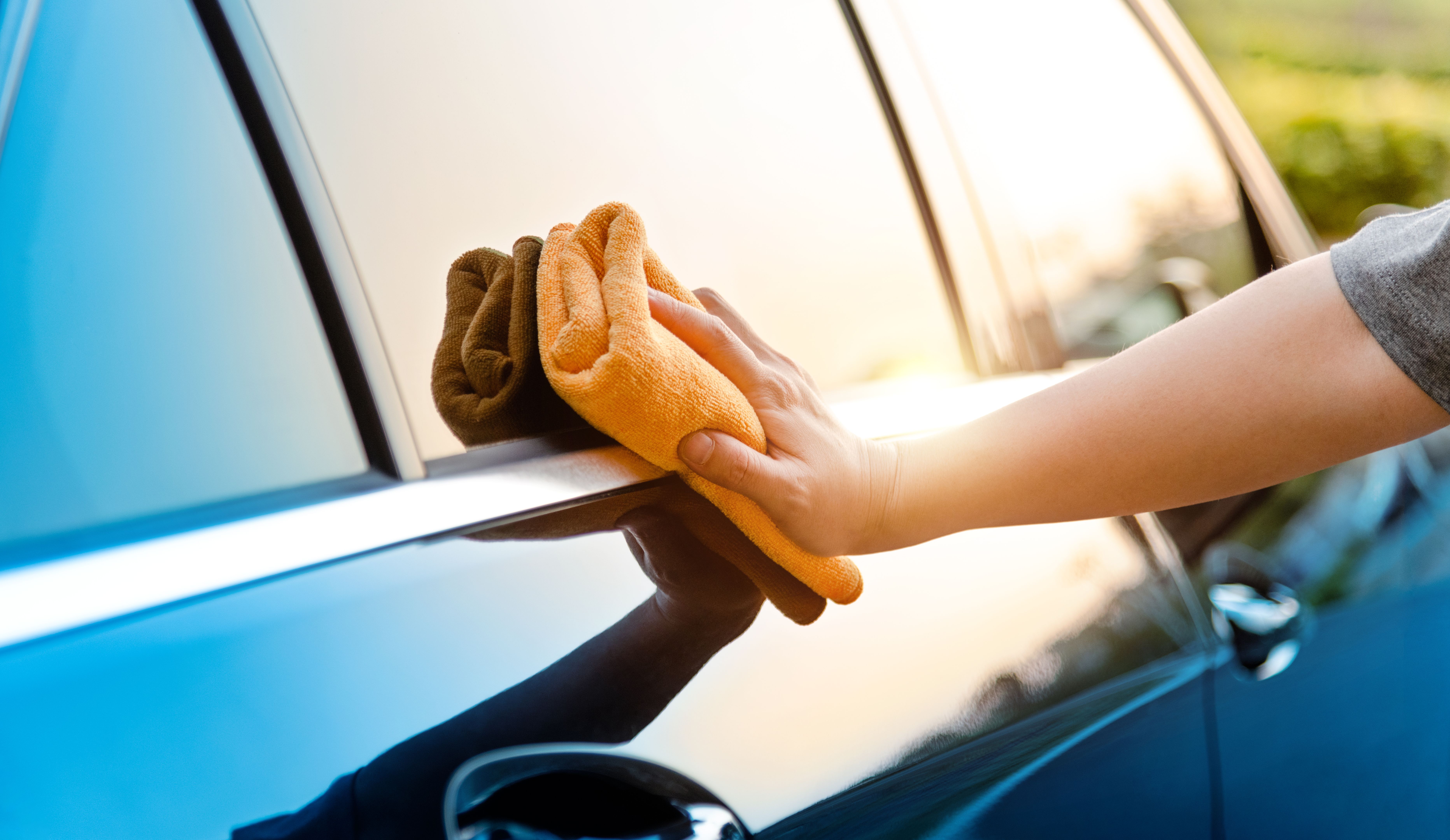 Woman hand cleaning car with a cloth
