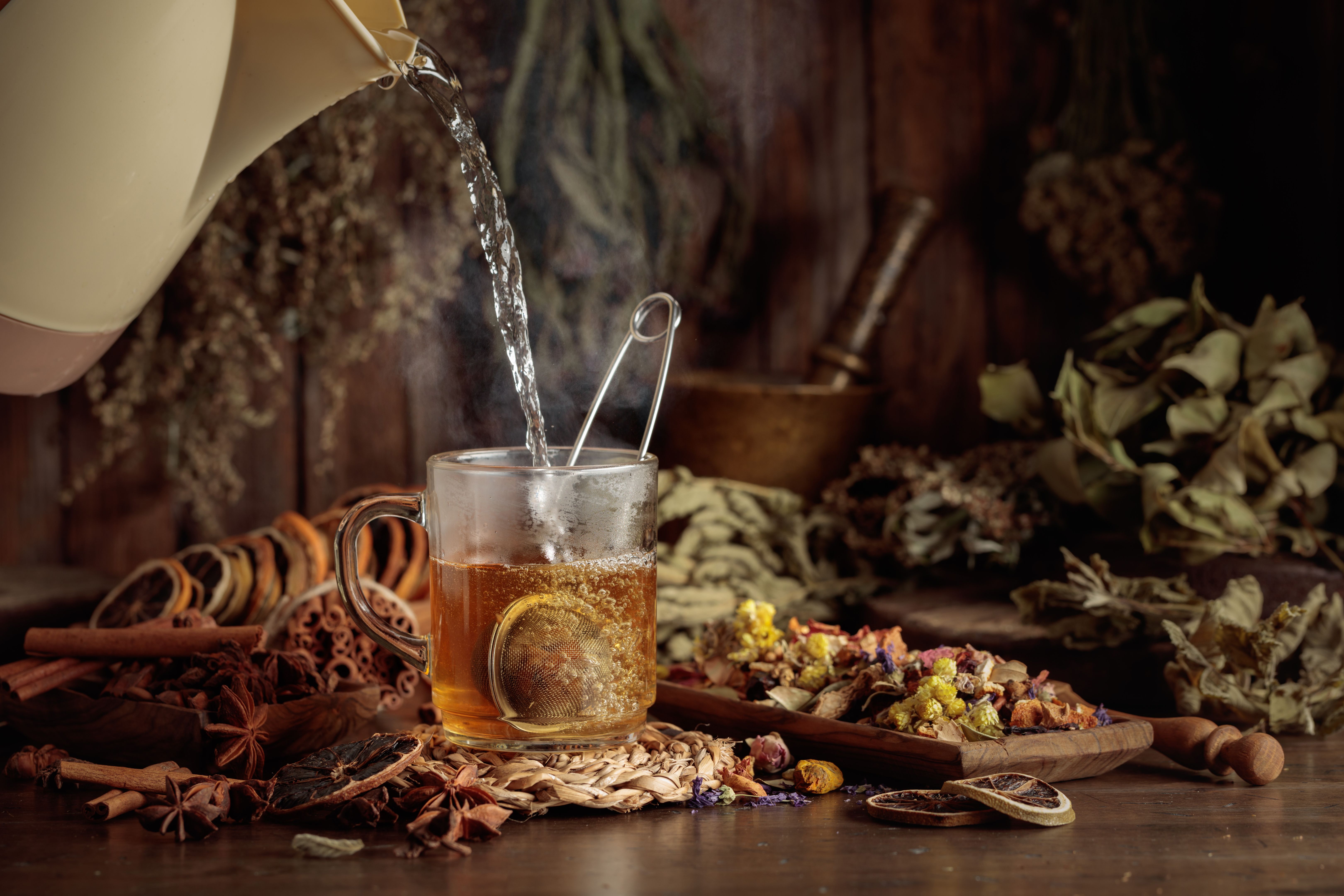 Glass of herbal tea with various dried herbs, flowers, and spices.