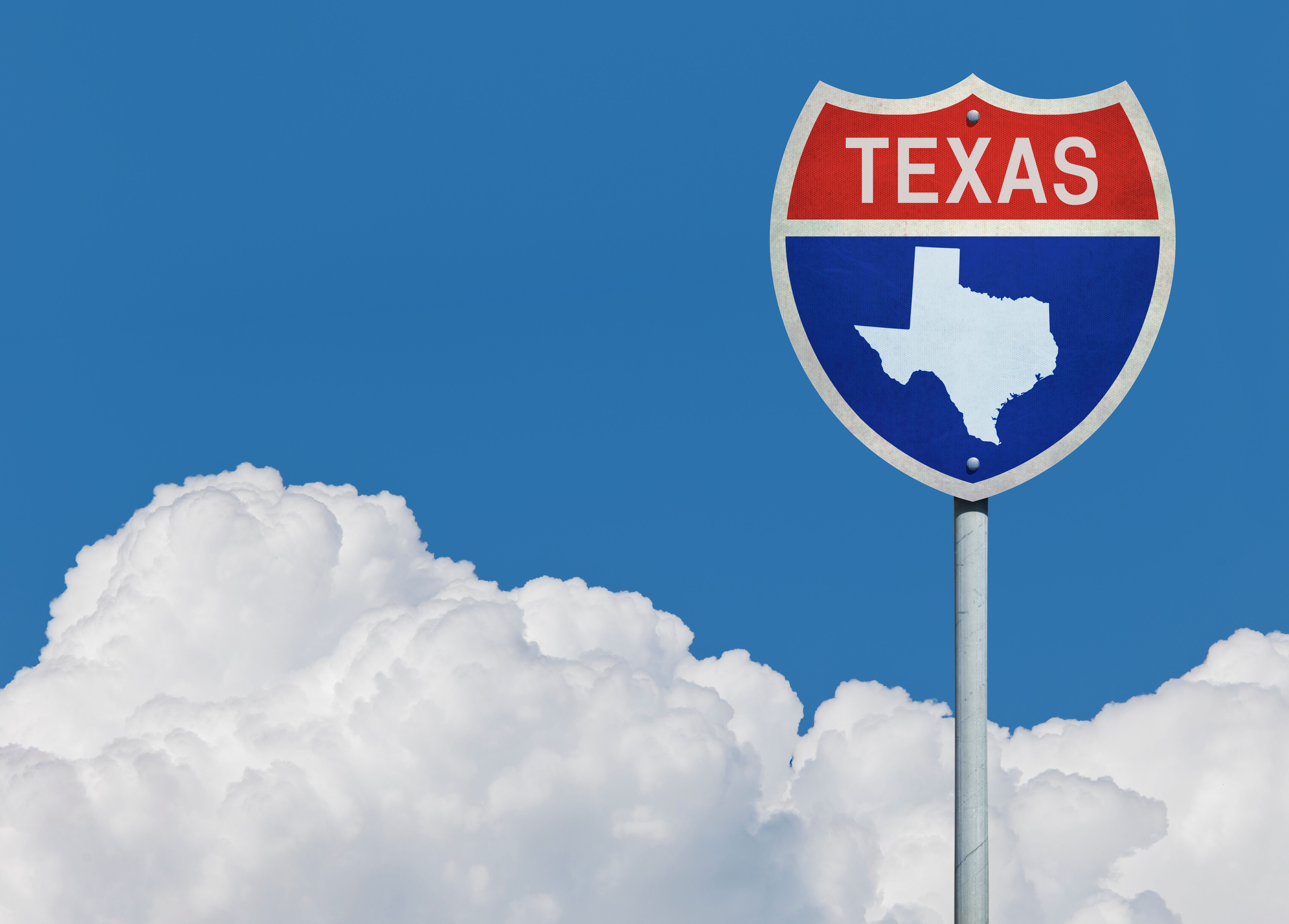 Highway sign for Interstate road in Texas with map in front of clouds Highway sign for Interstate road in Texas with map in front of clouds