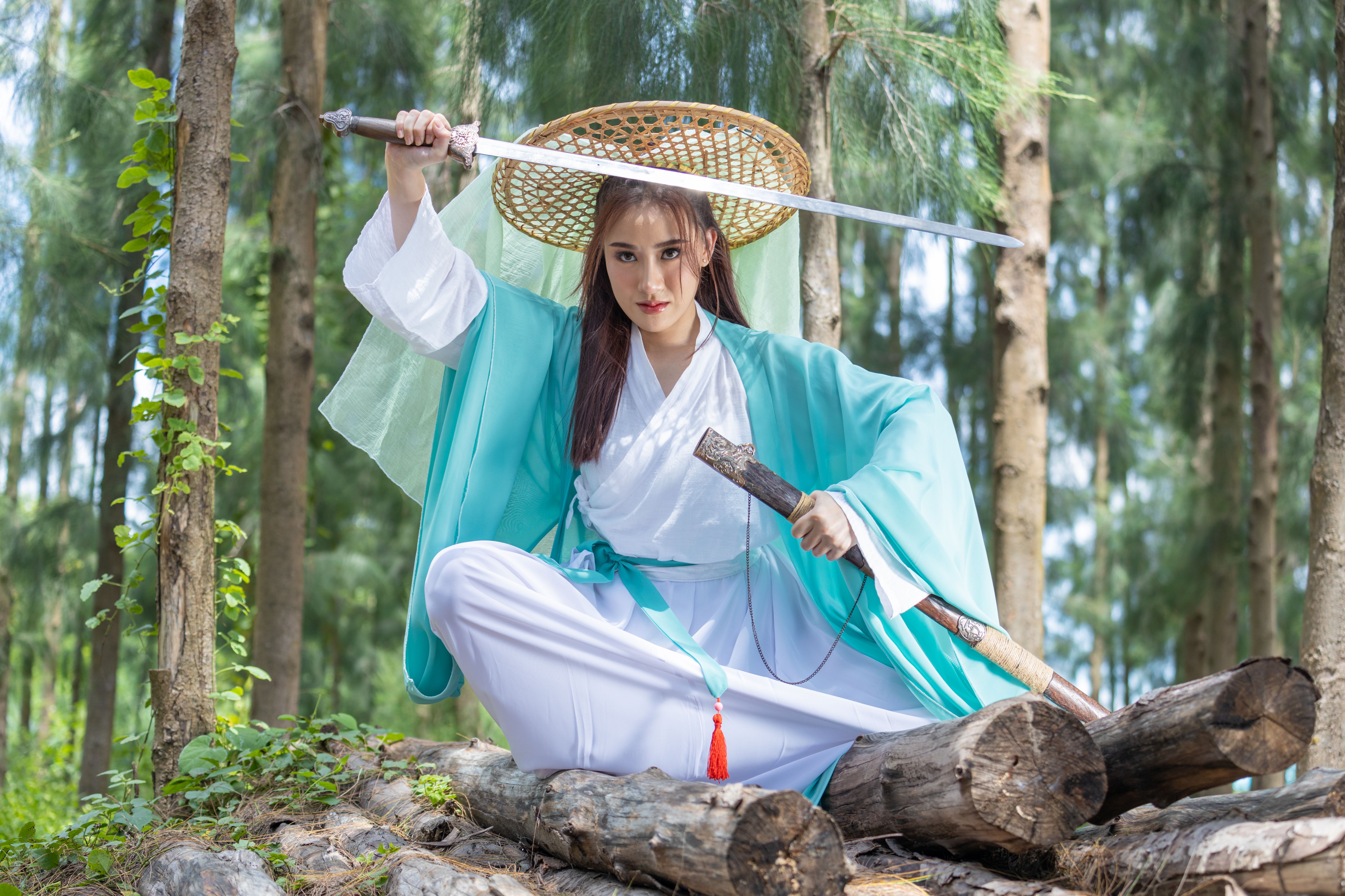 Young beautiful Asian woman dressed in ancient Chinese warrior style with ancient fan. cute girl in green dress