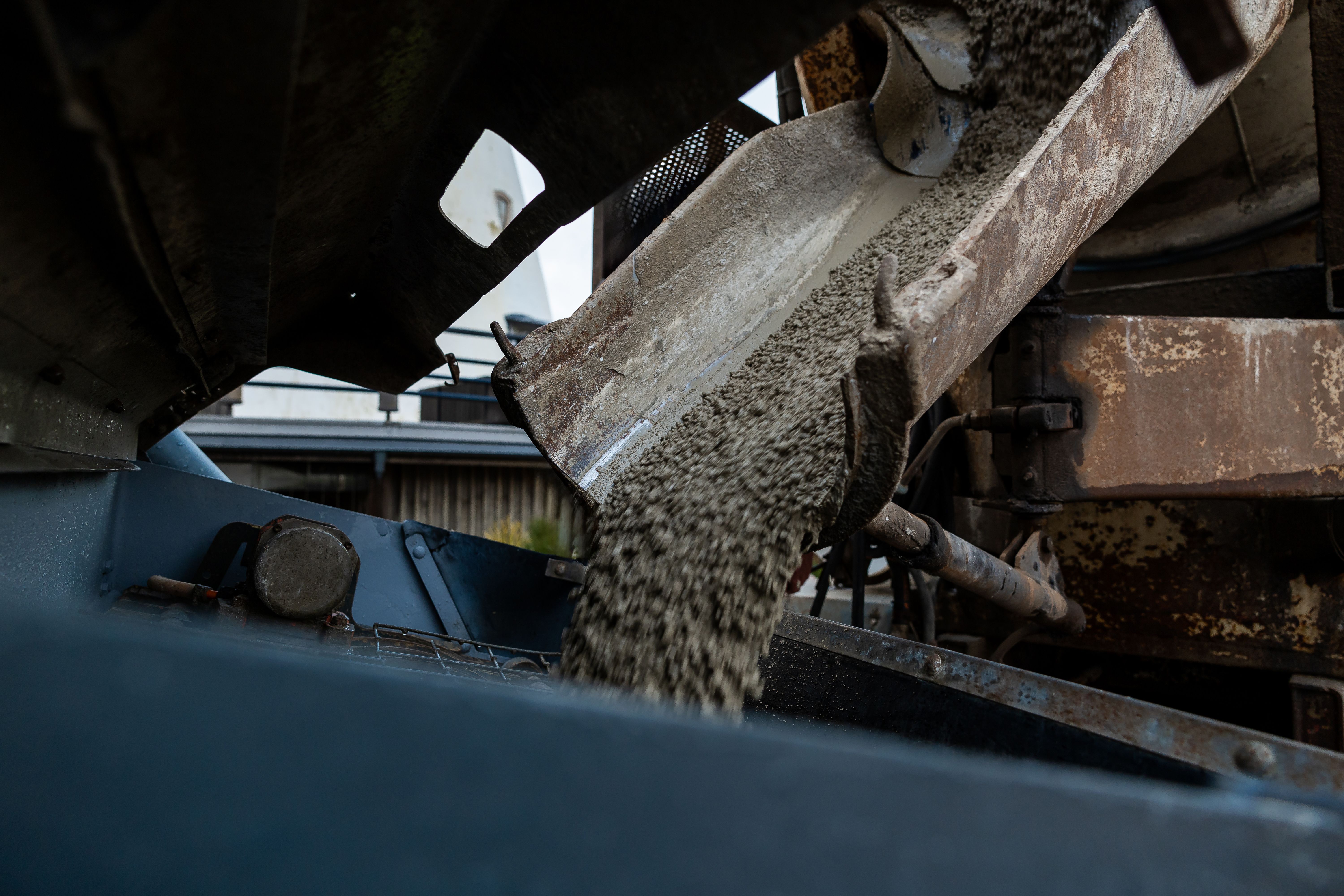 Close-up of Concrete Pouring from a Mixer Truck Chute into a Foundation at a Construction Site