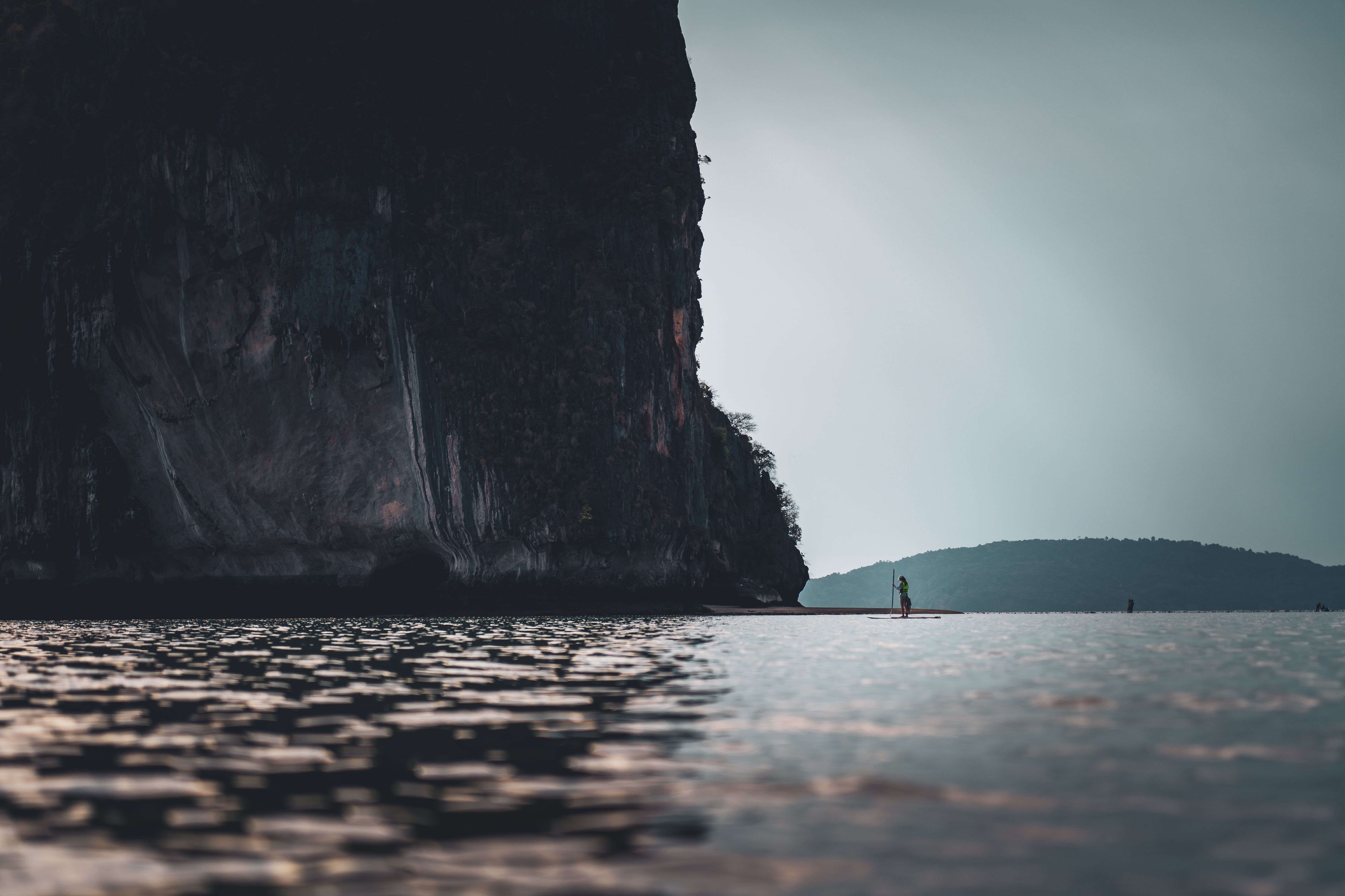 A woman with her surfboard standing in front of giant island (Krabi province Thailand) A woman with her surfboard standing in front of giant island (Krabi province Thailand)