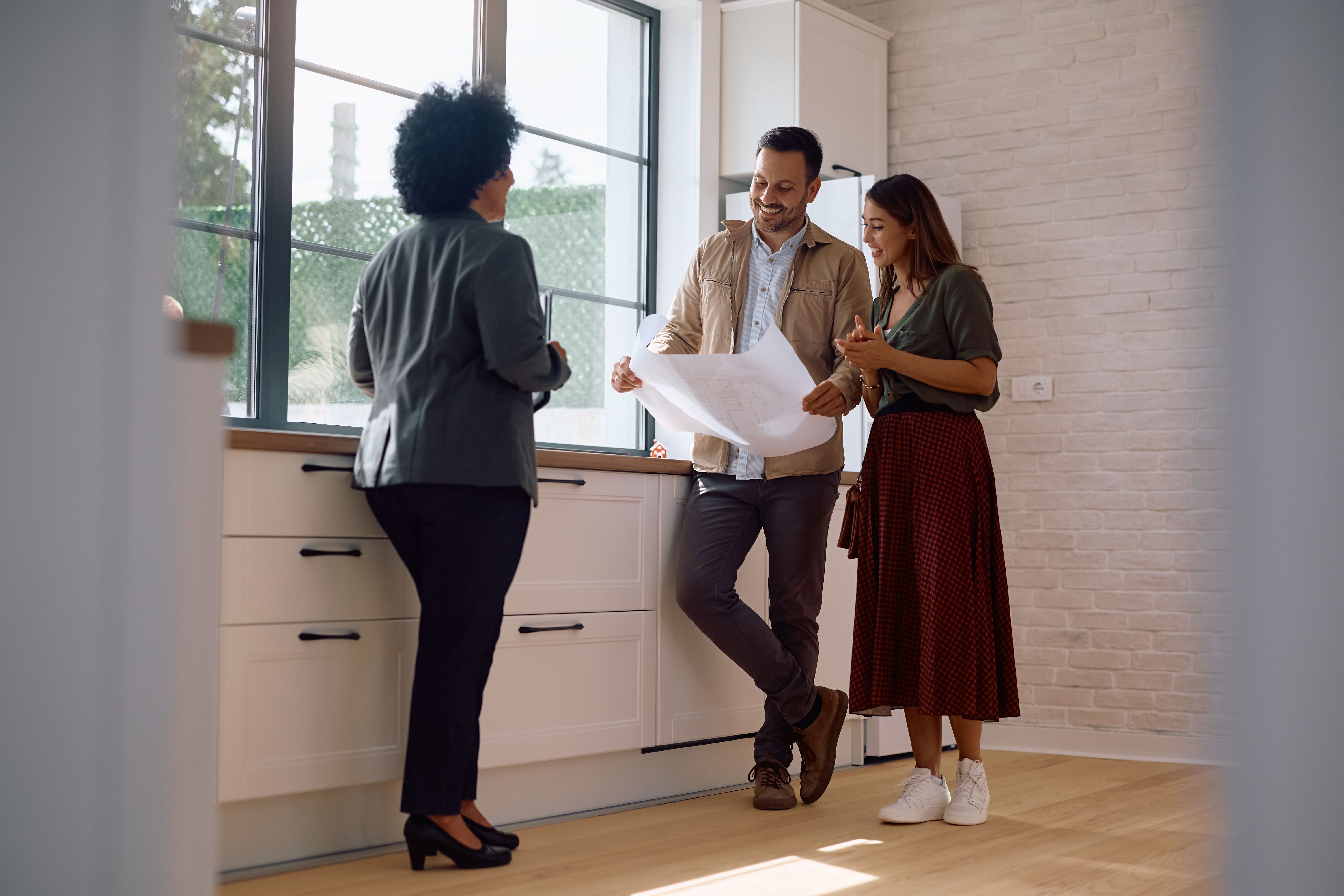 Happy couple of property buyers analyzing housing plans with their real estate agent. Happy couple of property buyers analyzing housing plans with their real estate agent.