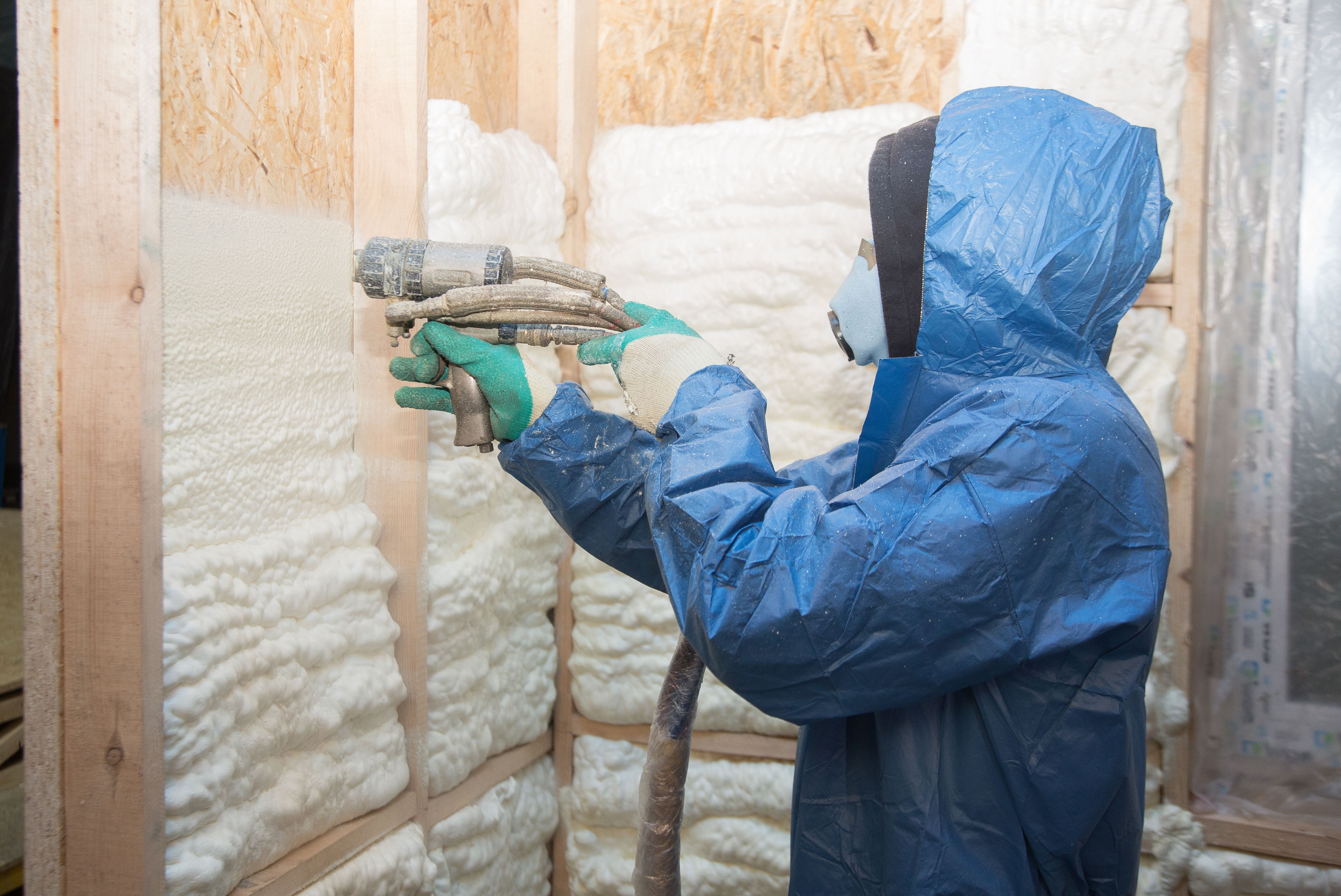 The worker insulates the walls of the house with foam for sound insulation and heat