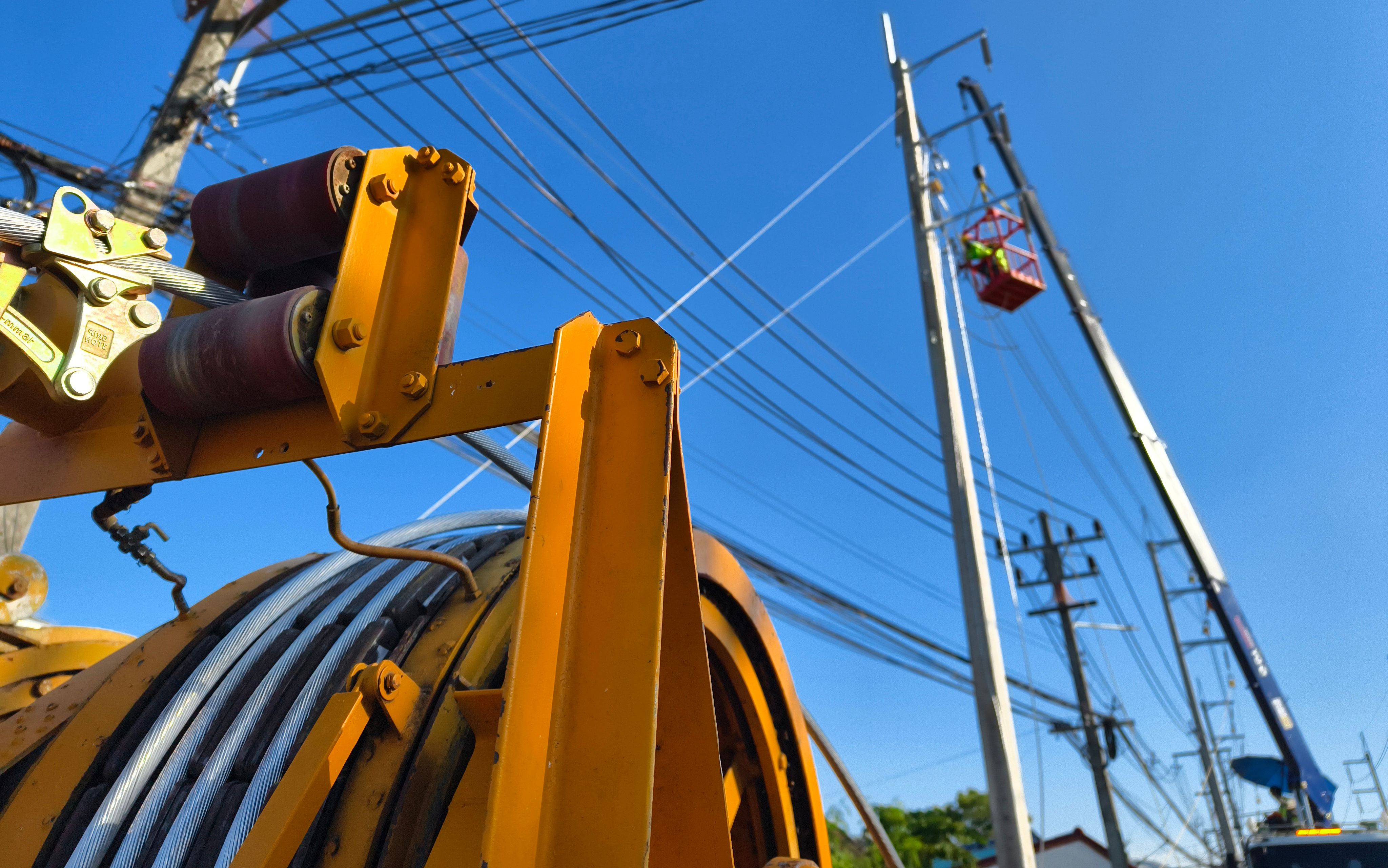 Installation of high-voltage electric wires on new poles along the road