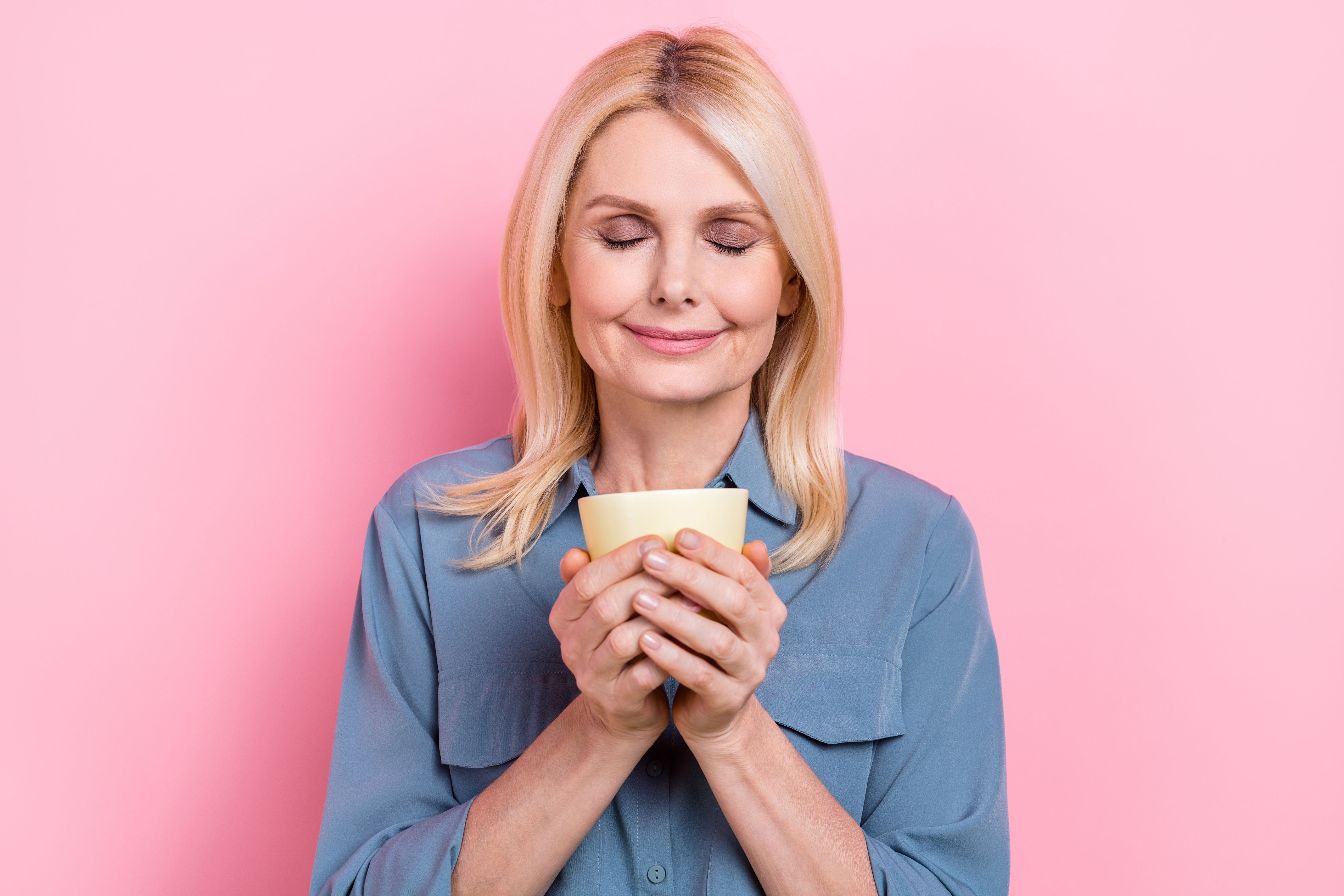 Closeup photo of lady mature age hold coffee cup smell aromatic fresh beverage relax time satisfied closed eyes isolated on pink color background