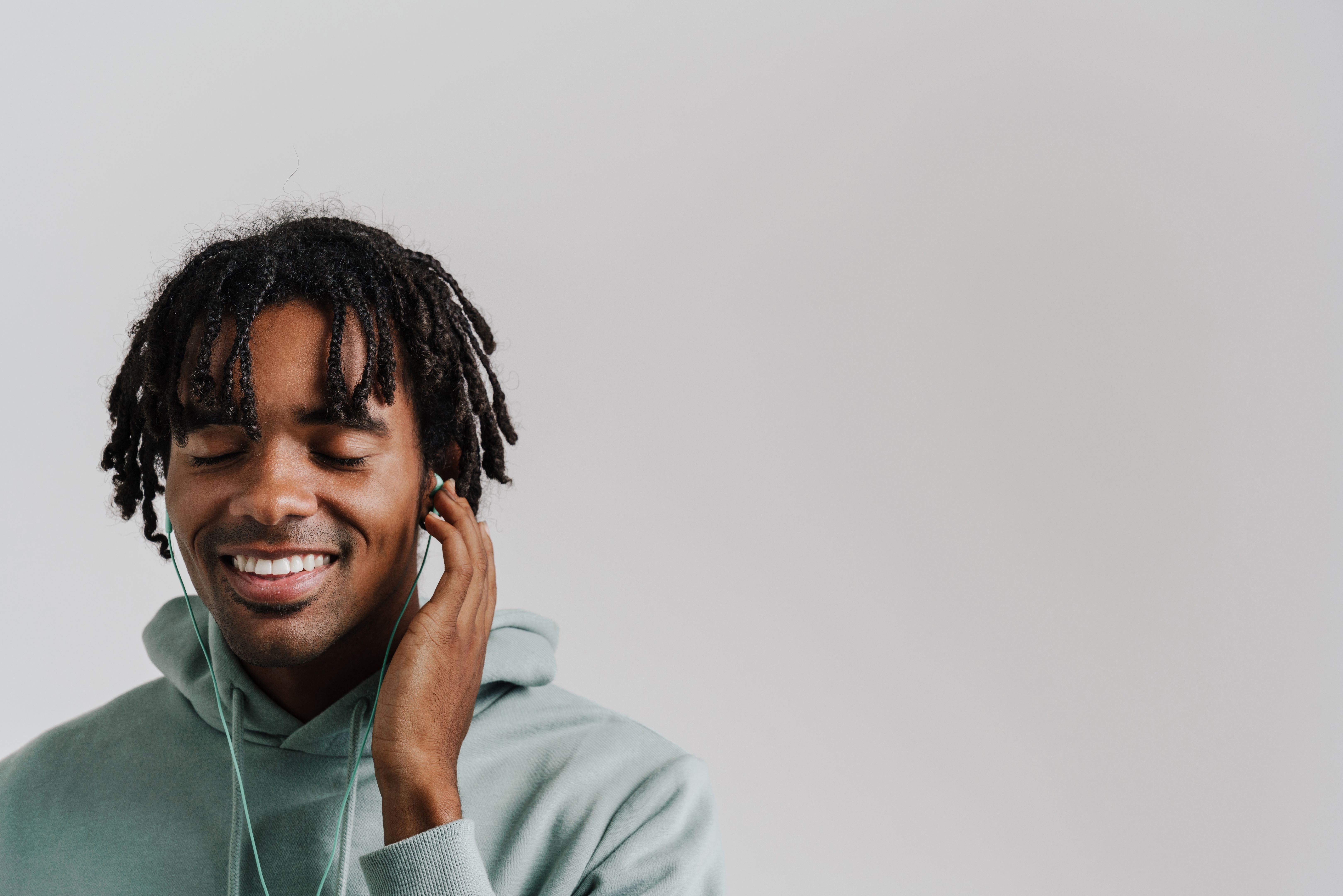 Excited young african man listening music with earphones isolated