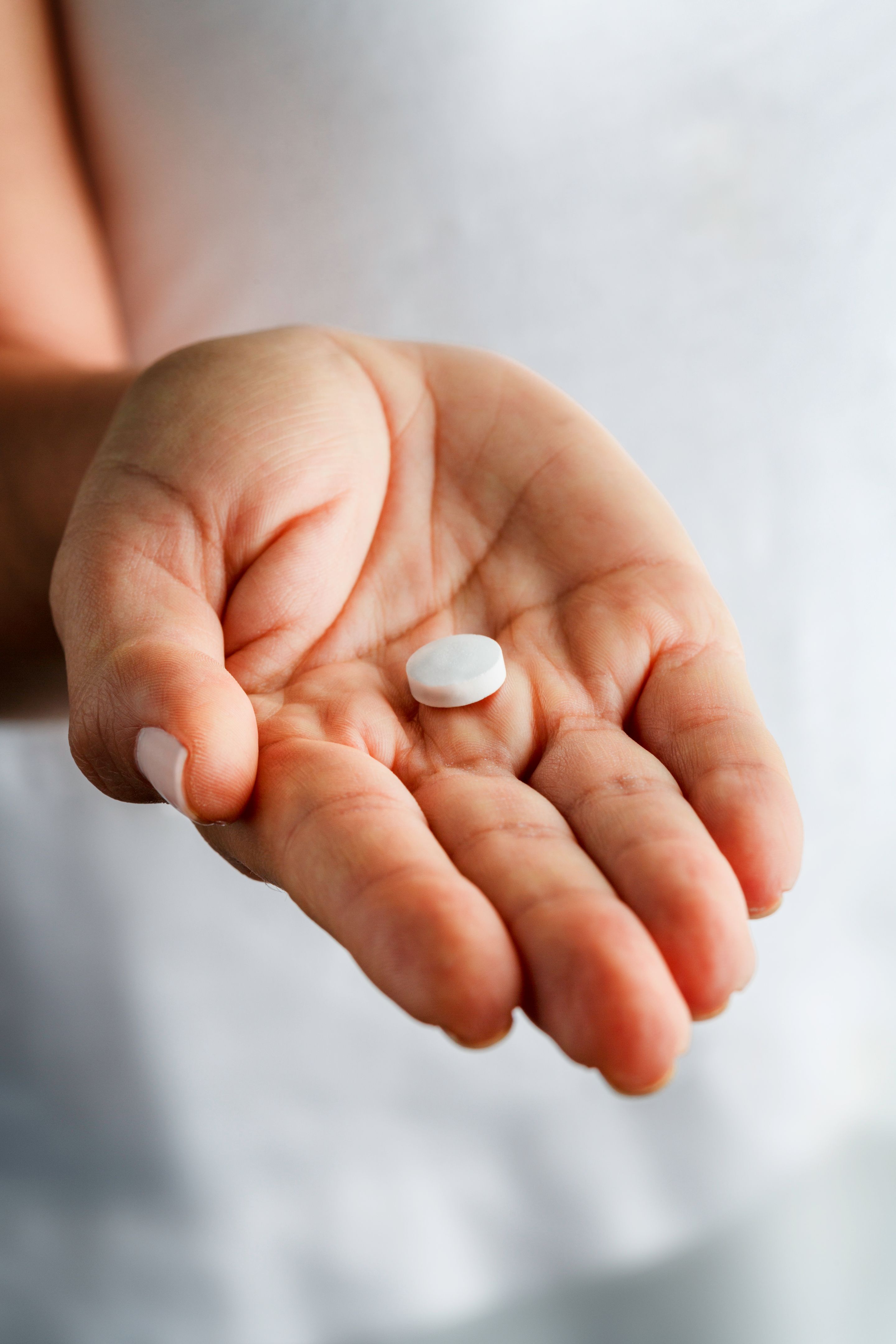 Single white aspirin pill on young woman hands Single white aspirin pill on young woman hands