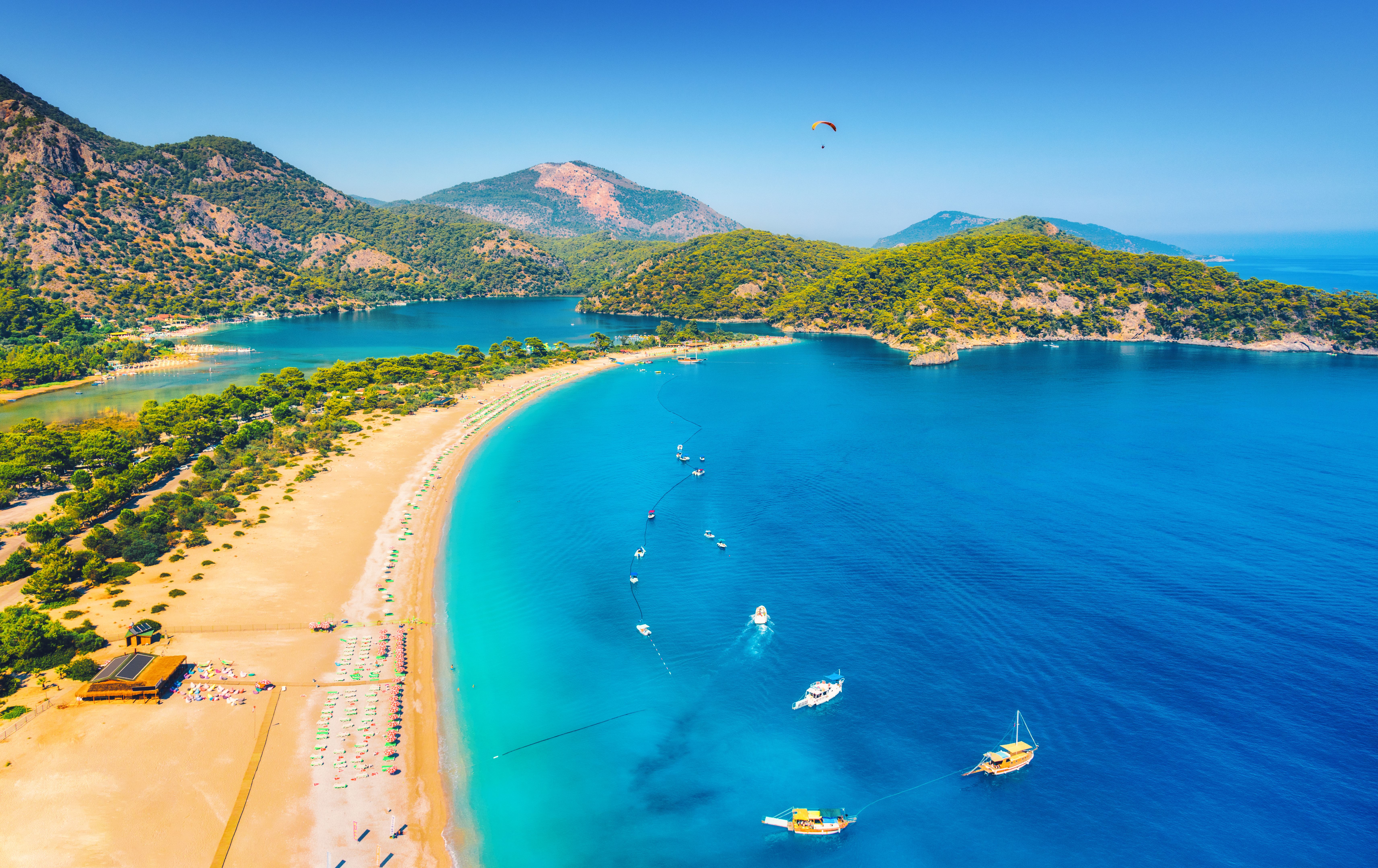 Amazing aerial view of Blue Lagoon in Oludeniz, Turkey. Summer landscape with sea spit, boats and yachts, green trees, azure water, sandy beach in sunny day. Travel. Top view of national park. Nature