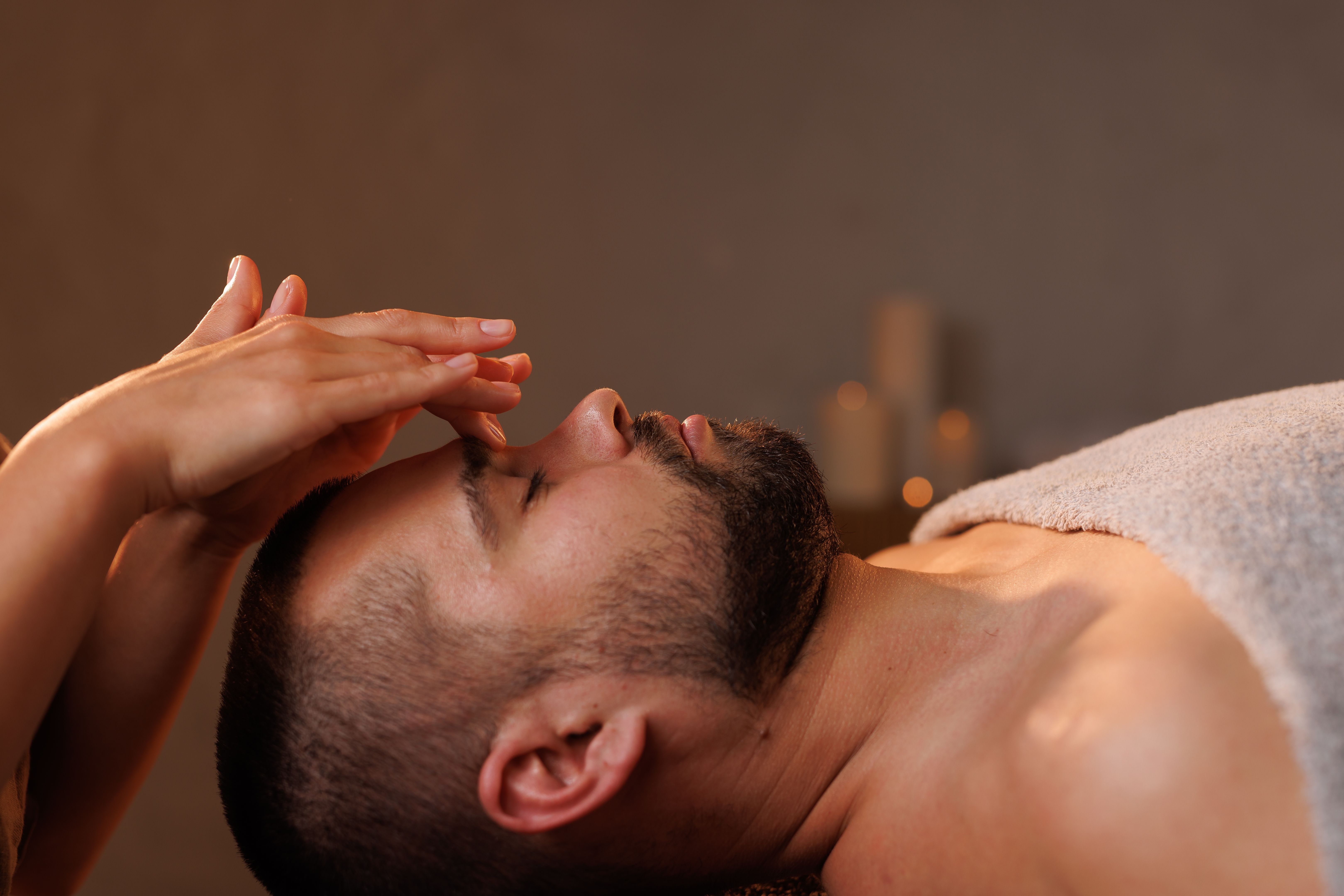 Masseuse giving man facial massage in calm relaxing atmosphere