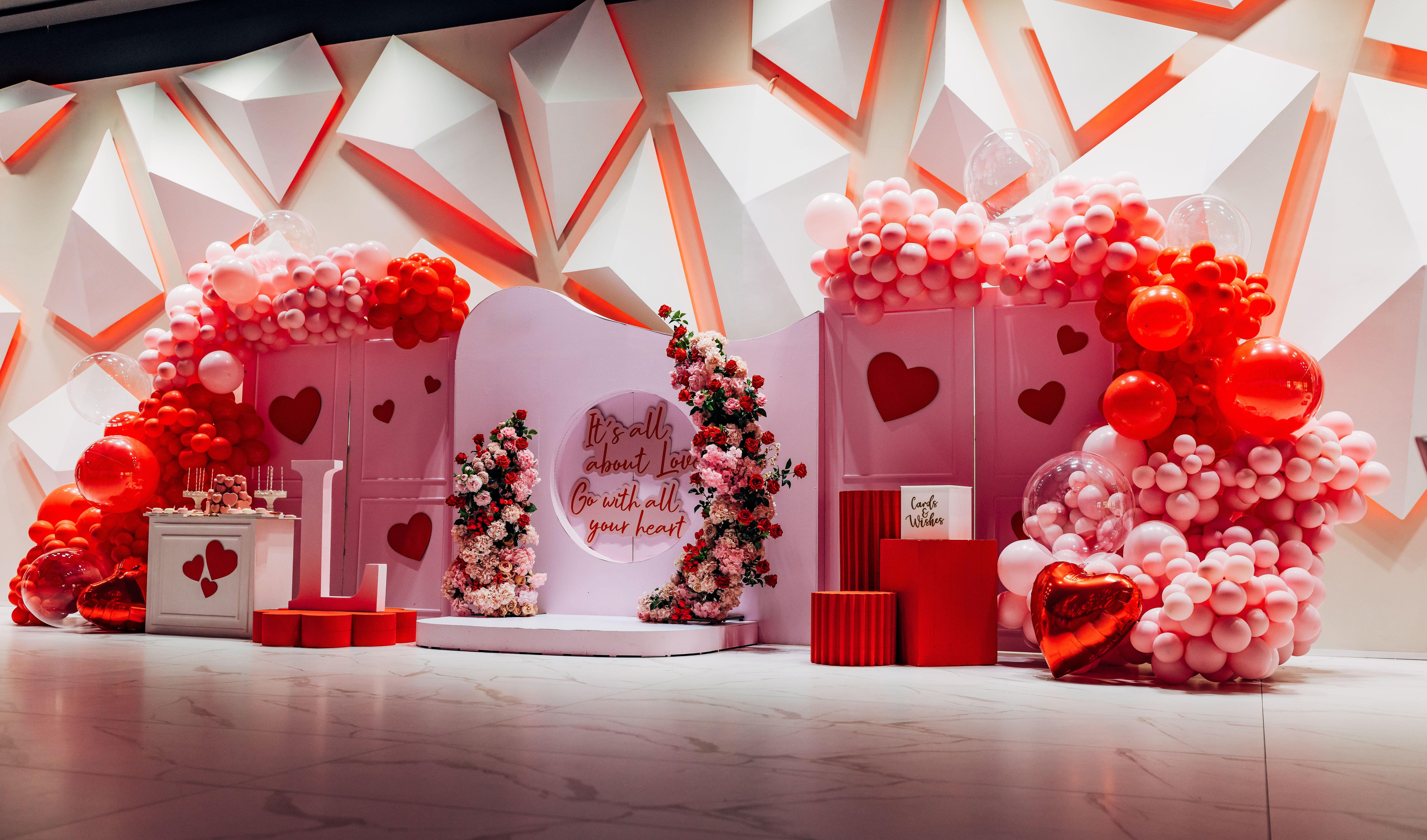 Arch decorated with red and pink balloons, flower arrangements. Photo wall decoration