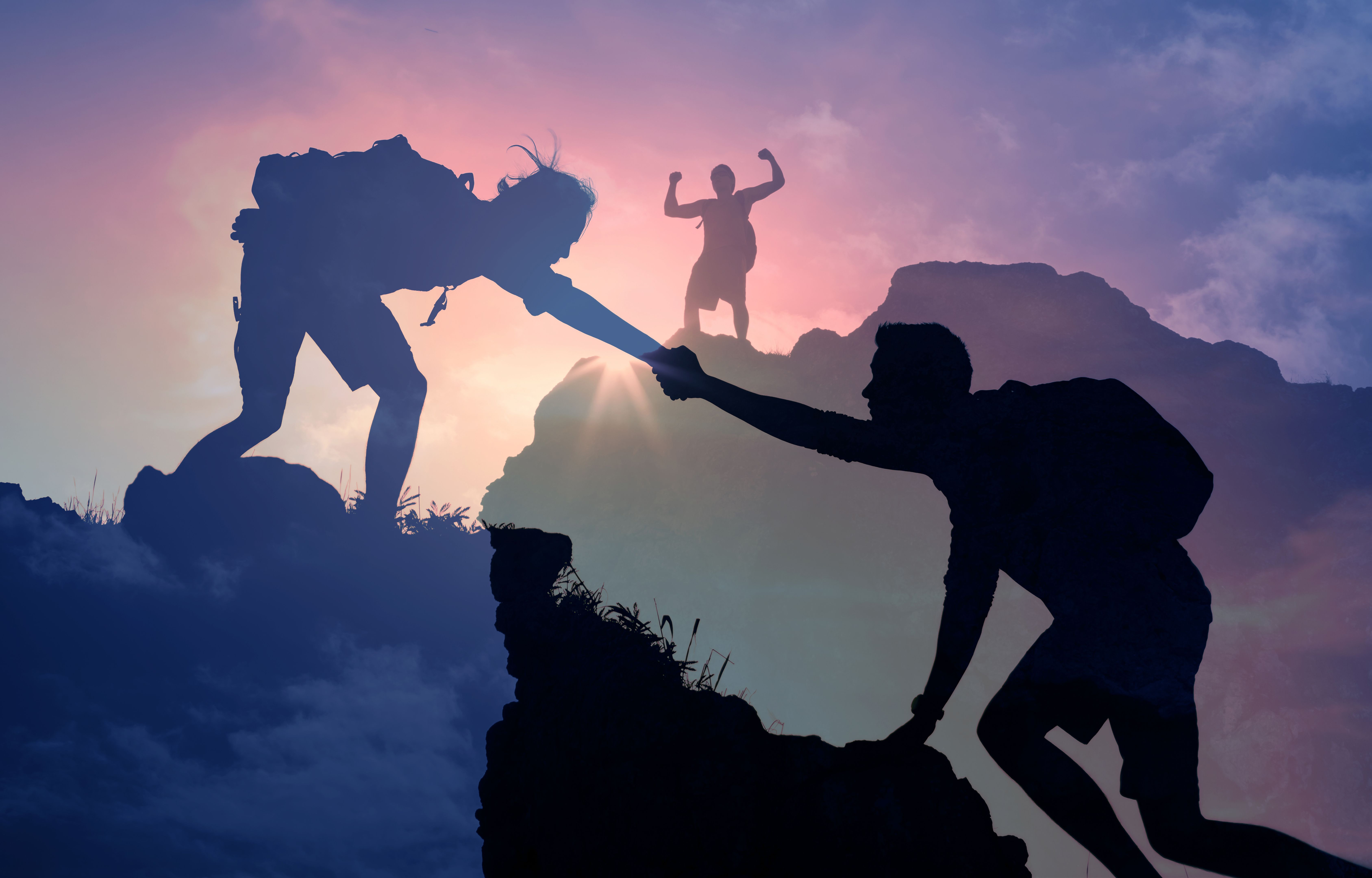 People helping each other hike up a mountain at sunrise. Giving a helping hand. People helping each other hike up a mountain at sunrise. Giving a helping hand.