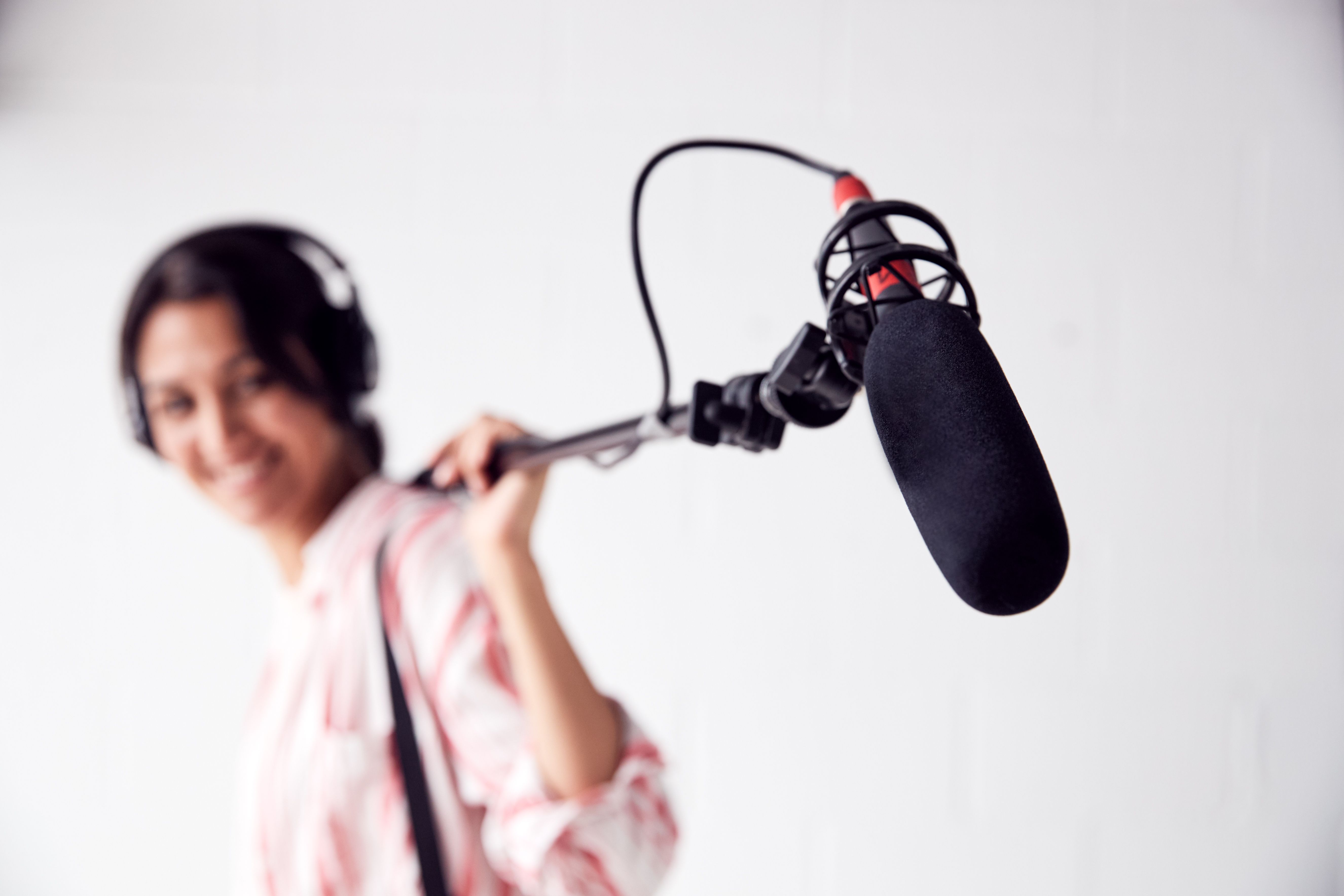 Portrait Of Female Sound Recordist Holding Microphone On Video Film Production In White Studio Portrait Of Female Sound Recordist Holding Microphone On Video Film Production In White Studio