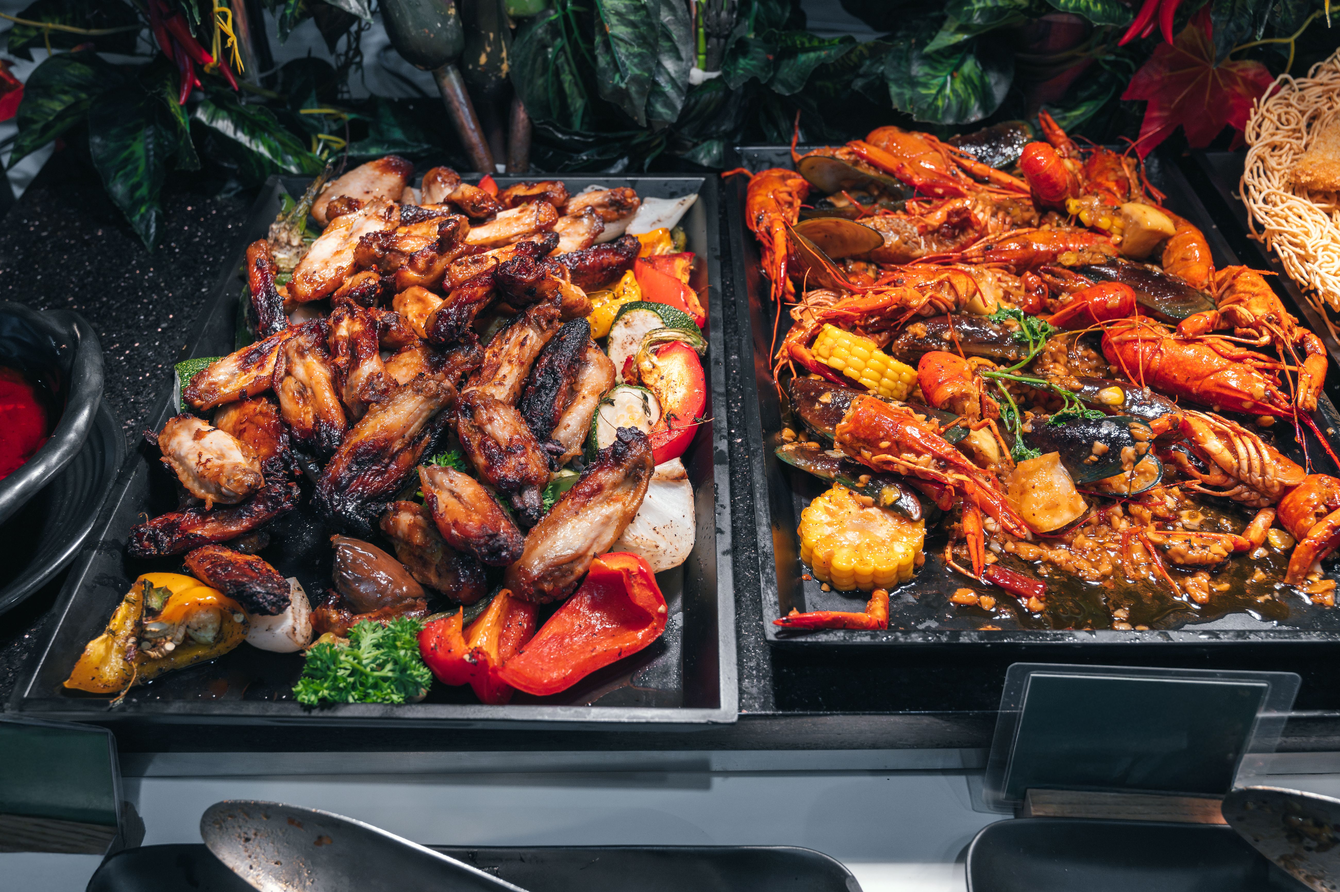 hot dishes garnish at Asian buffet in hotel restaurant for breakfast. Fried chicken meat and crayfish at Asian night market in Vietnam