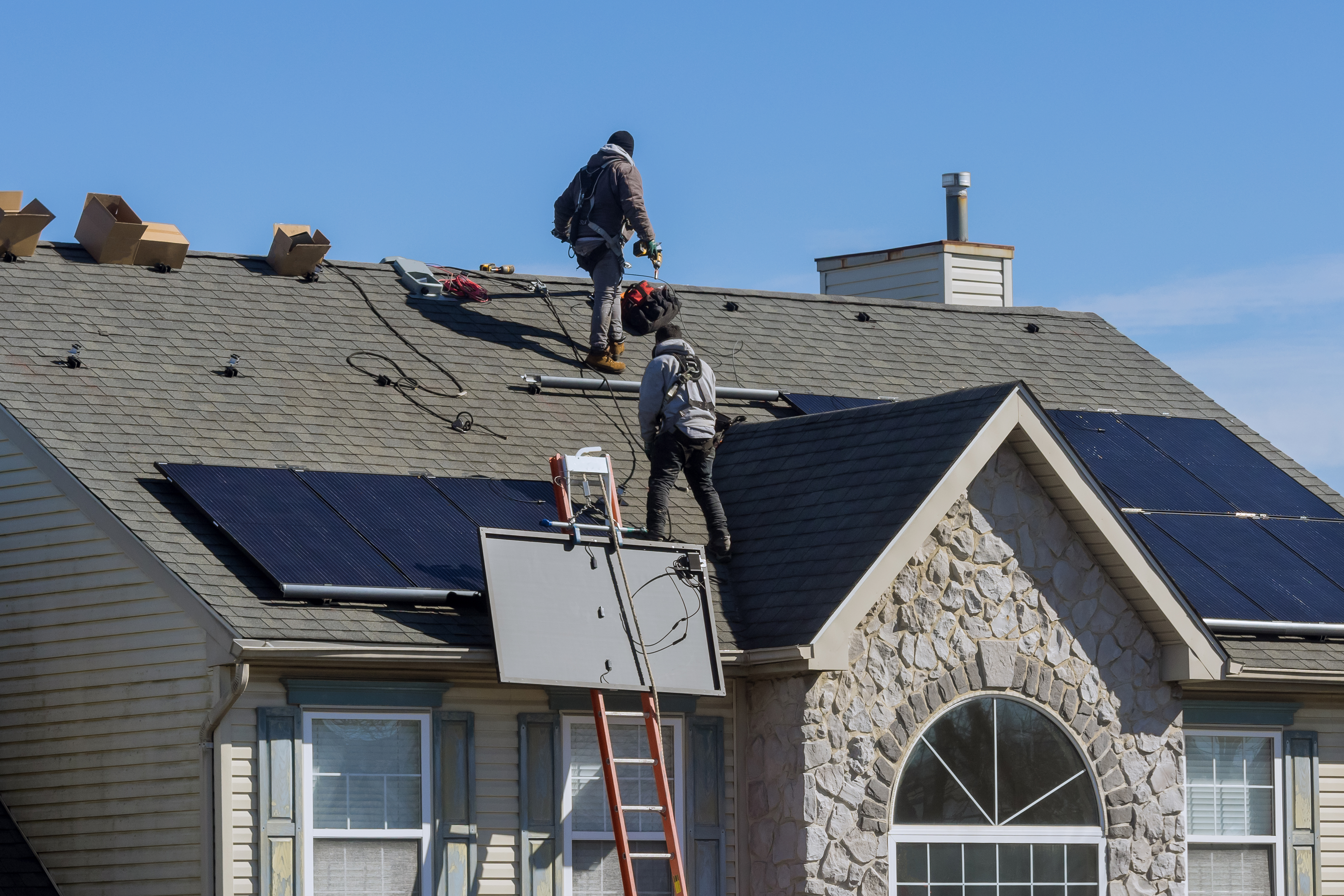 Technician workers installing alternative energy photovoltaic solar panels on roof