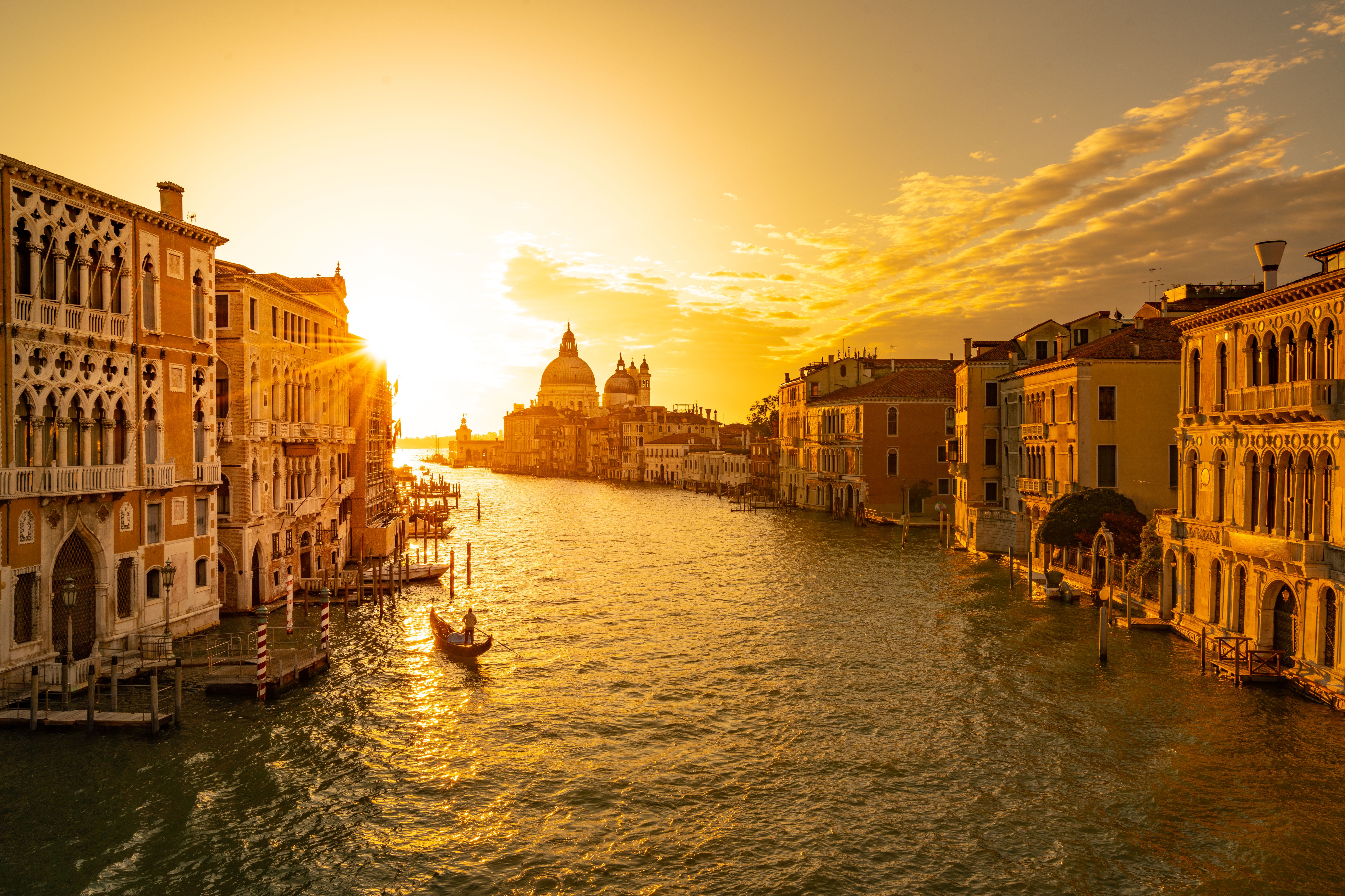 Sunrise over the canale grande (grand canal) in venice with one single gondolieri in his traditional gondola