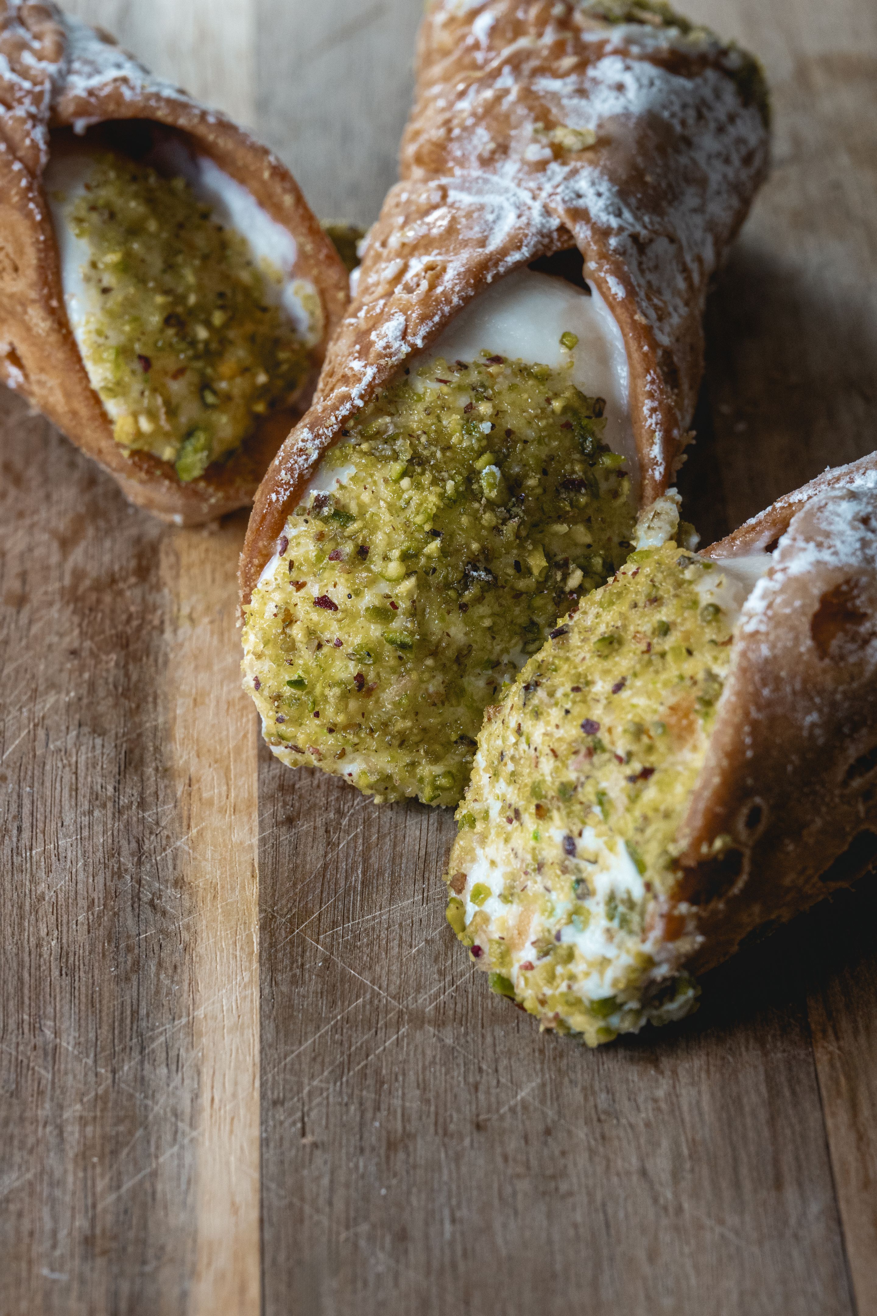 Traditional Sicilian cannoli with pistachio topping on a wooden board