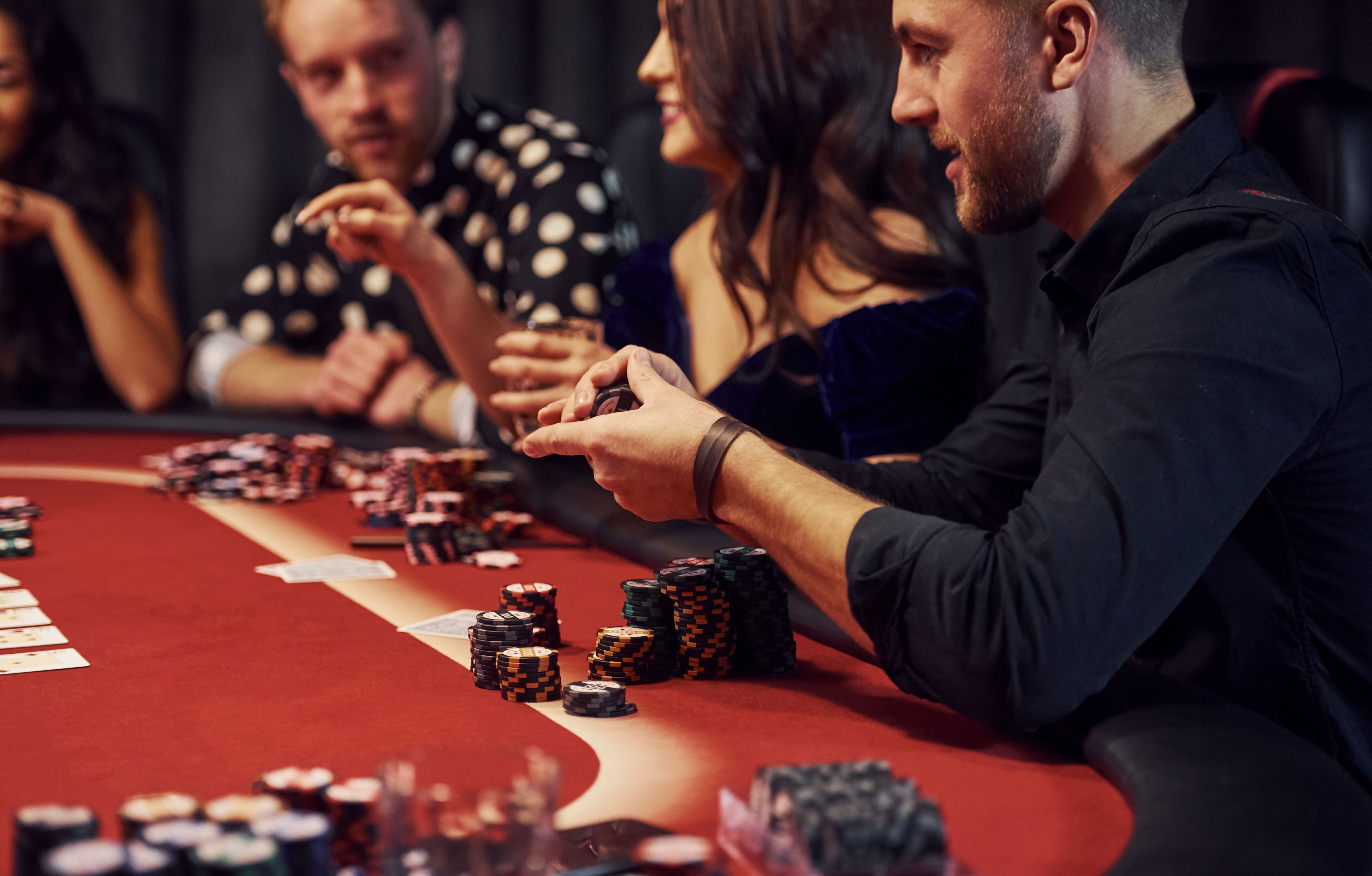 Group of elegant young people that playing poker in casino together Group of elegant young people that playing poker in casino together