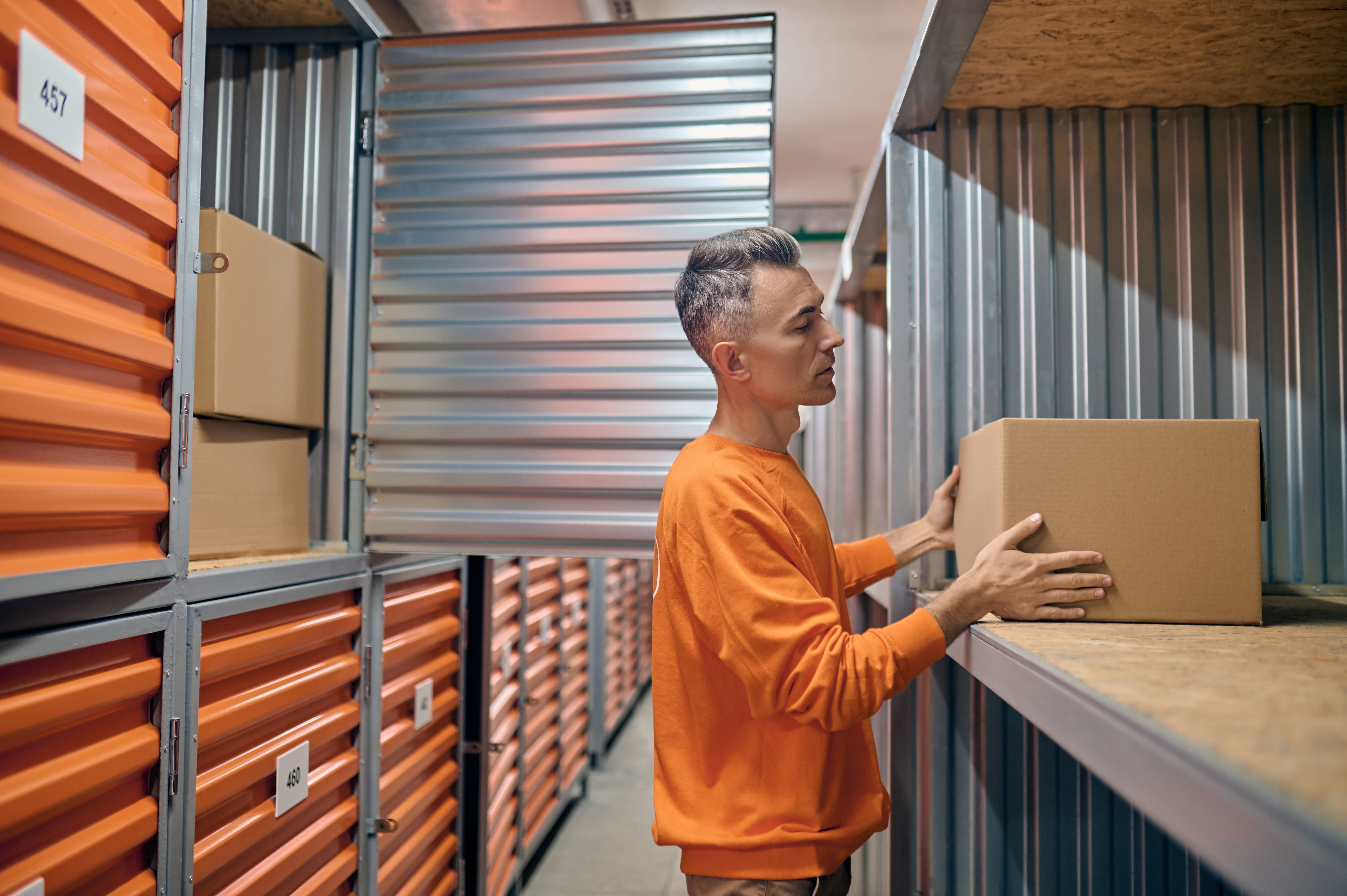 Concentrated warehouse employee placing goods into storage containers Concentrated warehouse employee placing goods into storage containers