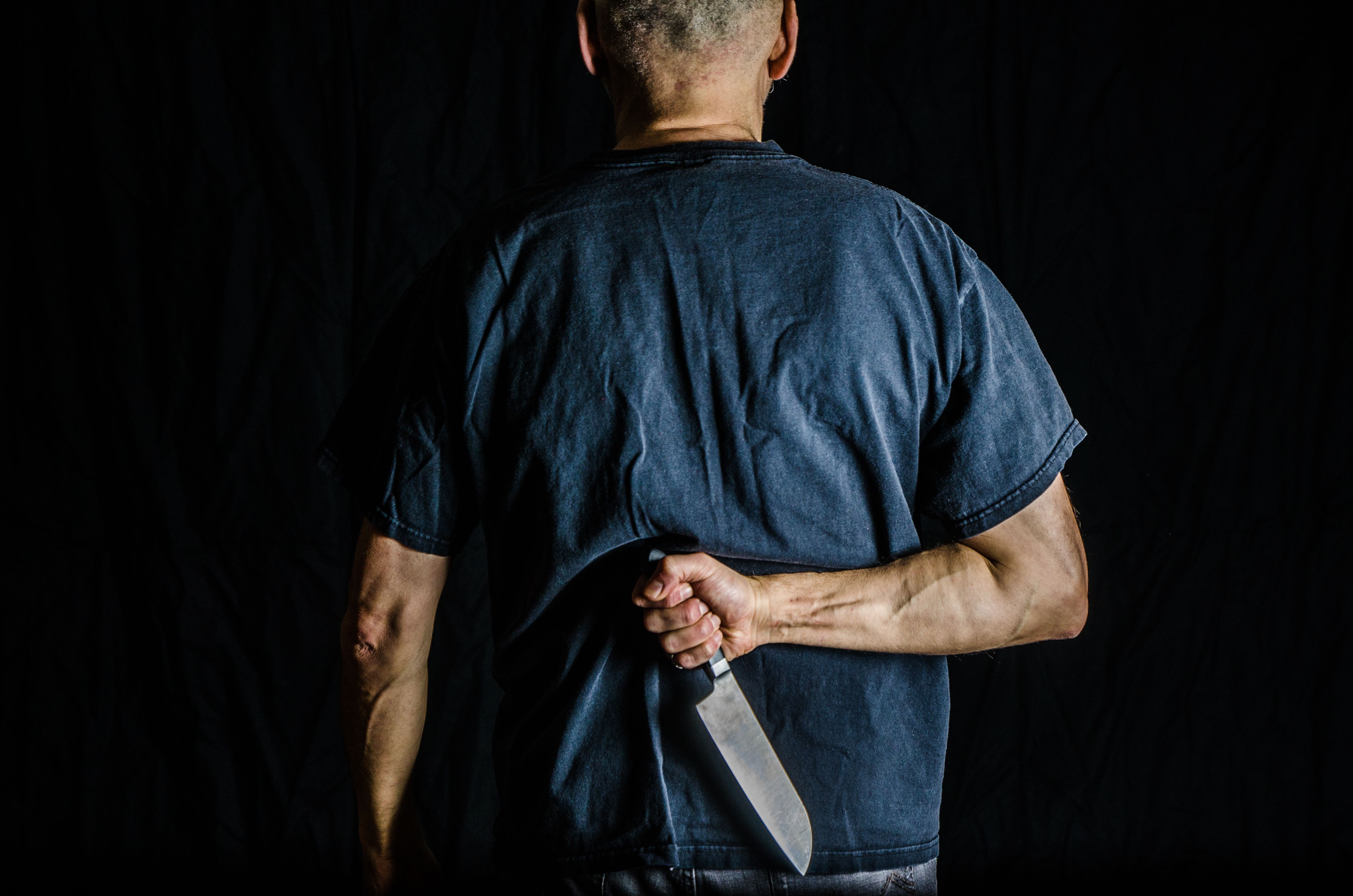 Man holding kitchen knife in his back