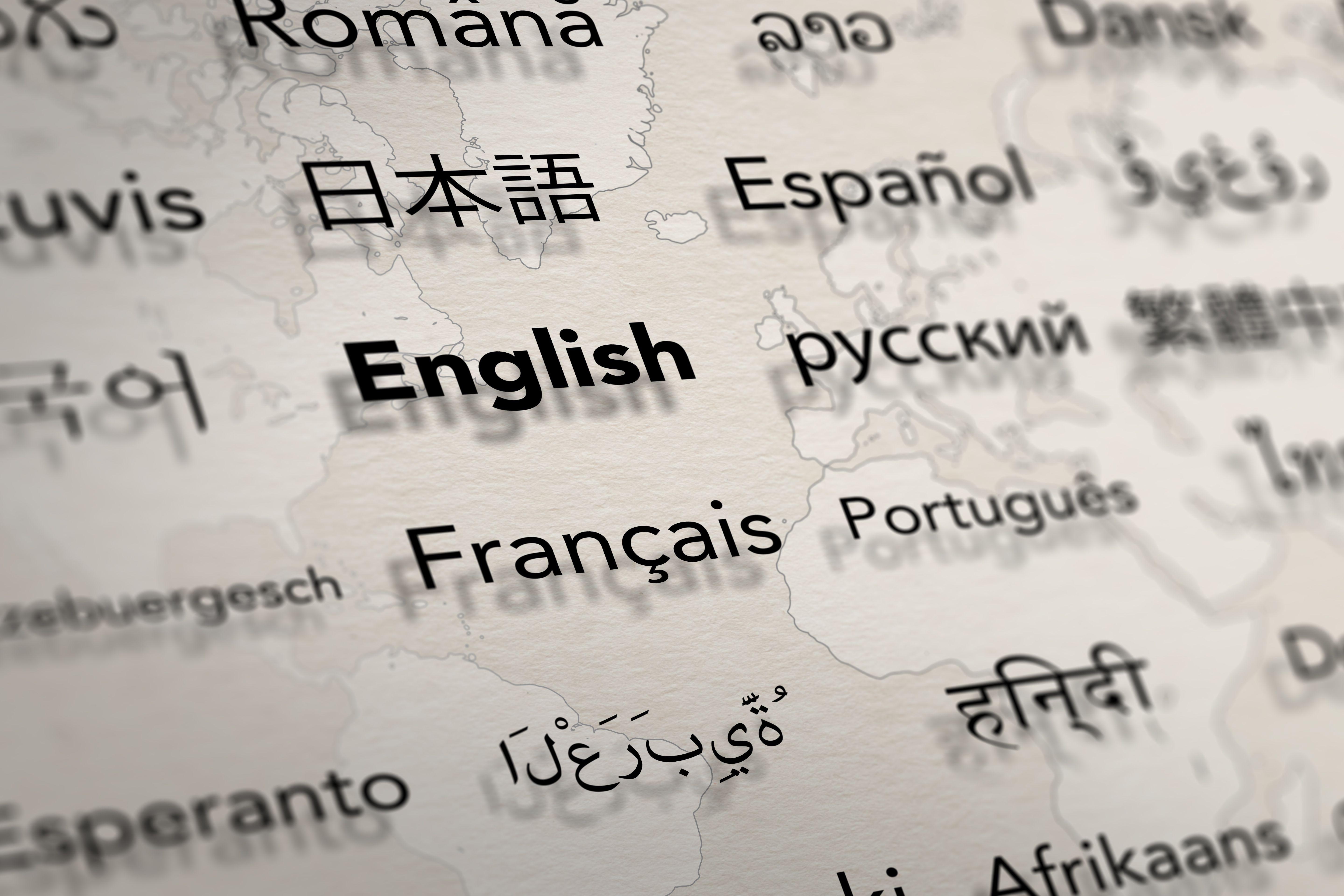 Several important languages on paper with world map background.