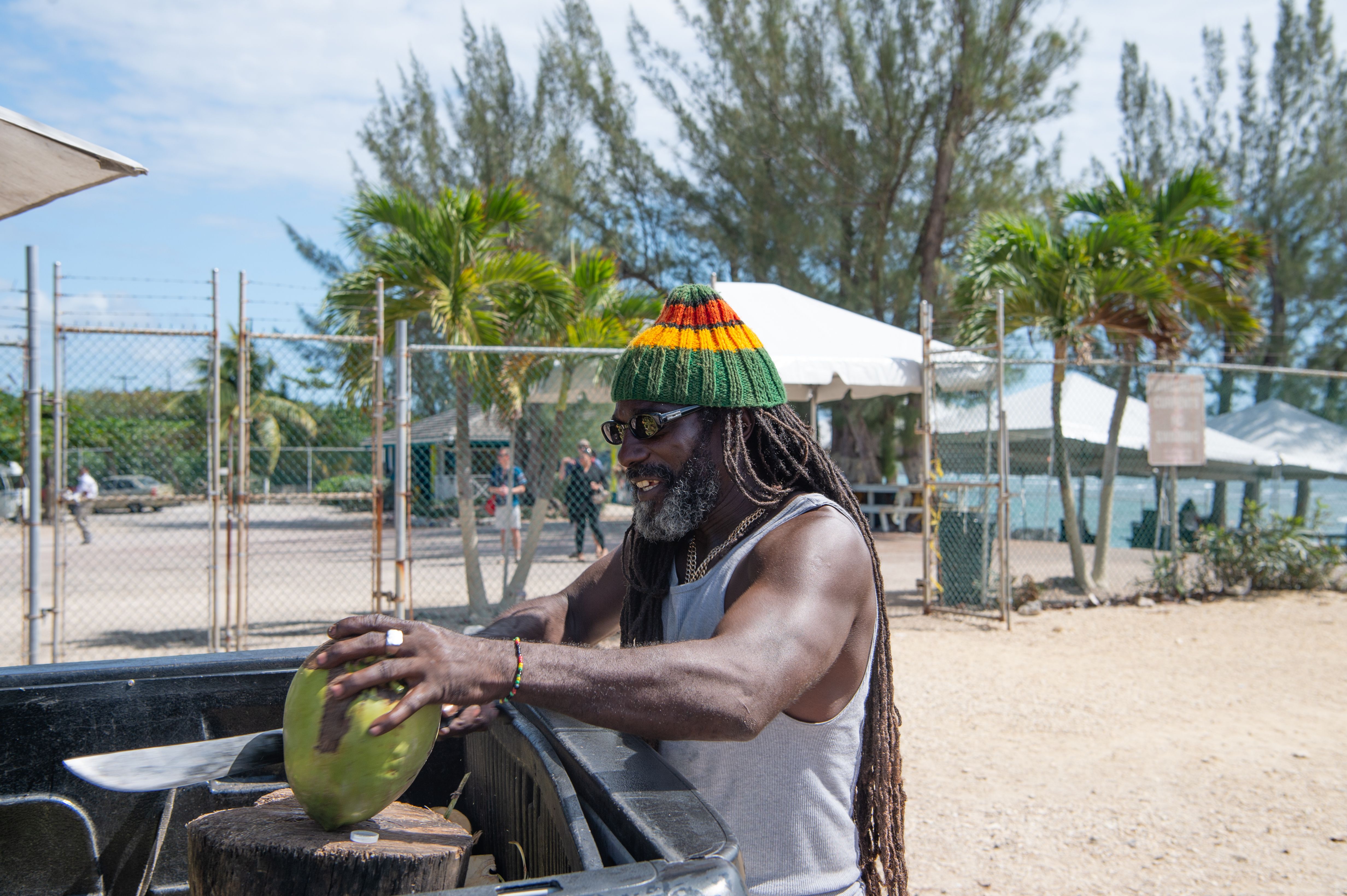 pitchman man with dreadlocks cut coconut outside